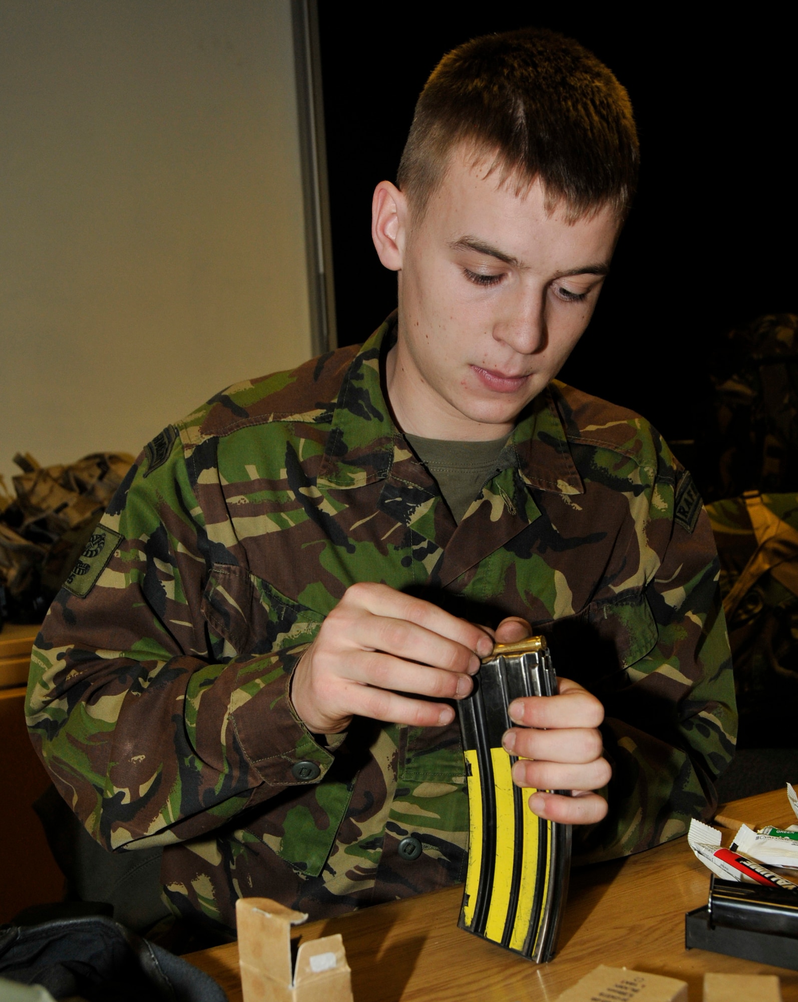 ROYAL AIR FORCE LAKENHEATH, England -- Royal Air Force Senior Aircraftman Ryan Loughran, 15th Regiment, laods ammo into a magazine during a joint tactical training exercise at the 48th Security Forces Squadron Defense University at RAF Feltwell on March 3, 2010. This joint training is the first of its kind. (Photo by Airman 1st Class Eboni Knox)