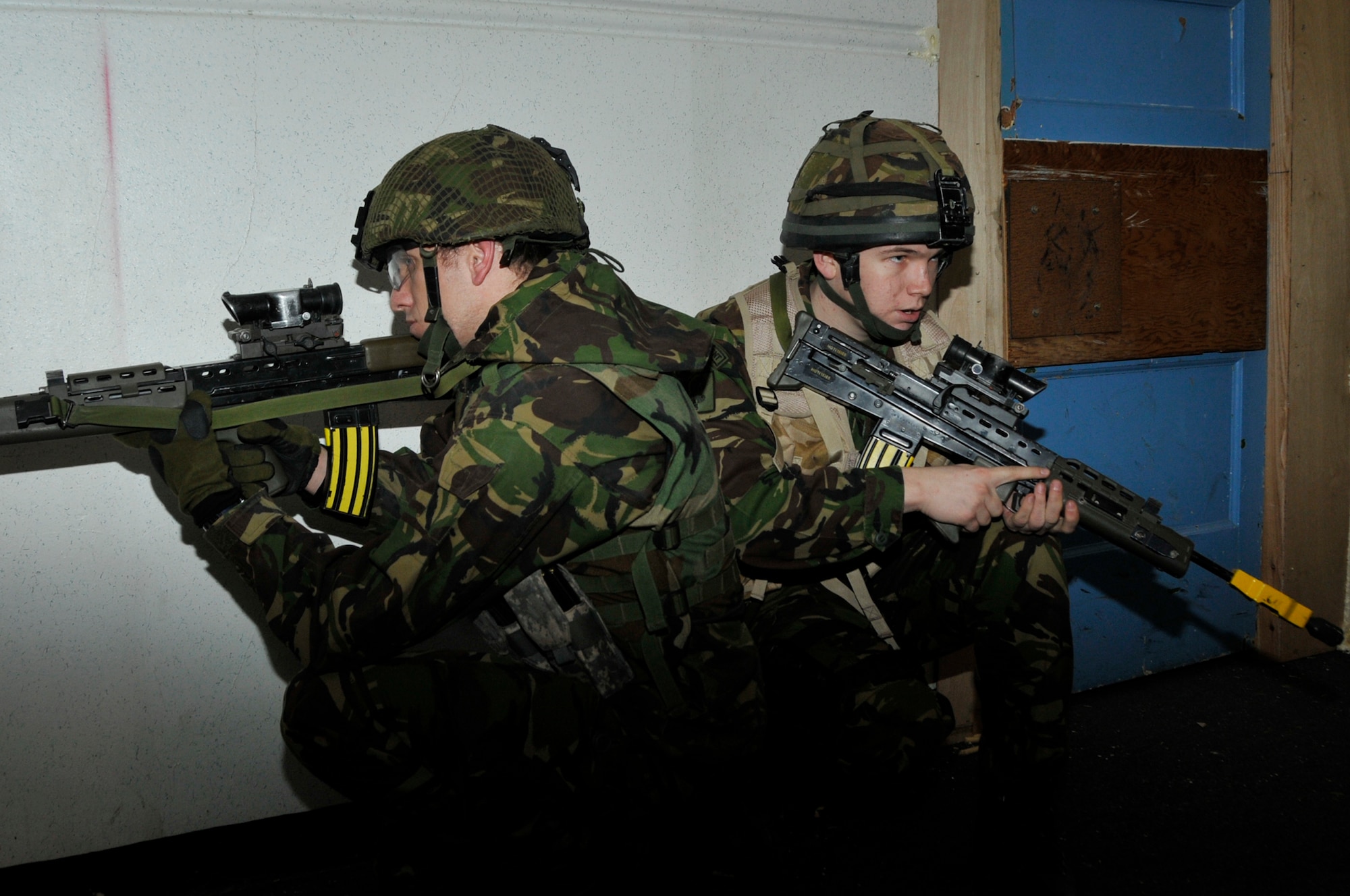 ROYAL AIR FORCE LAKENHEATH, England -- Two Royal Air Force airmen stay alert and on guard while clearing a room during a joint tactical training exercise at the 48th Security Forces Squadron Defense University at RAF Feltwell on March 3, 2010. Building clearing scenarios required teamwork and communication. (Photo by Airman 1st Class Eboni Knox)