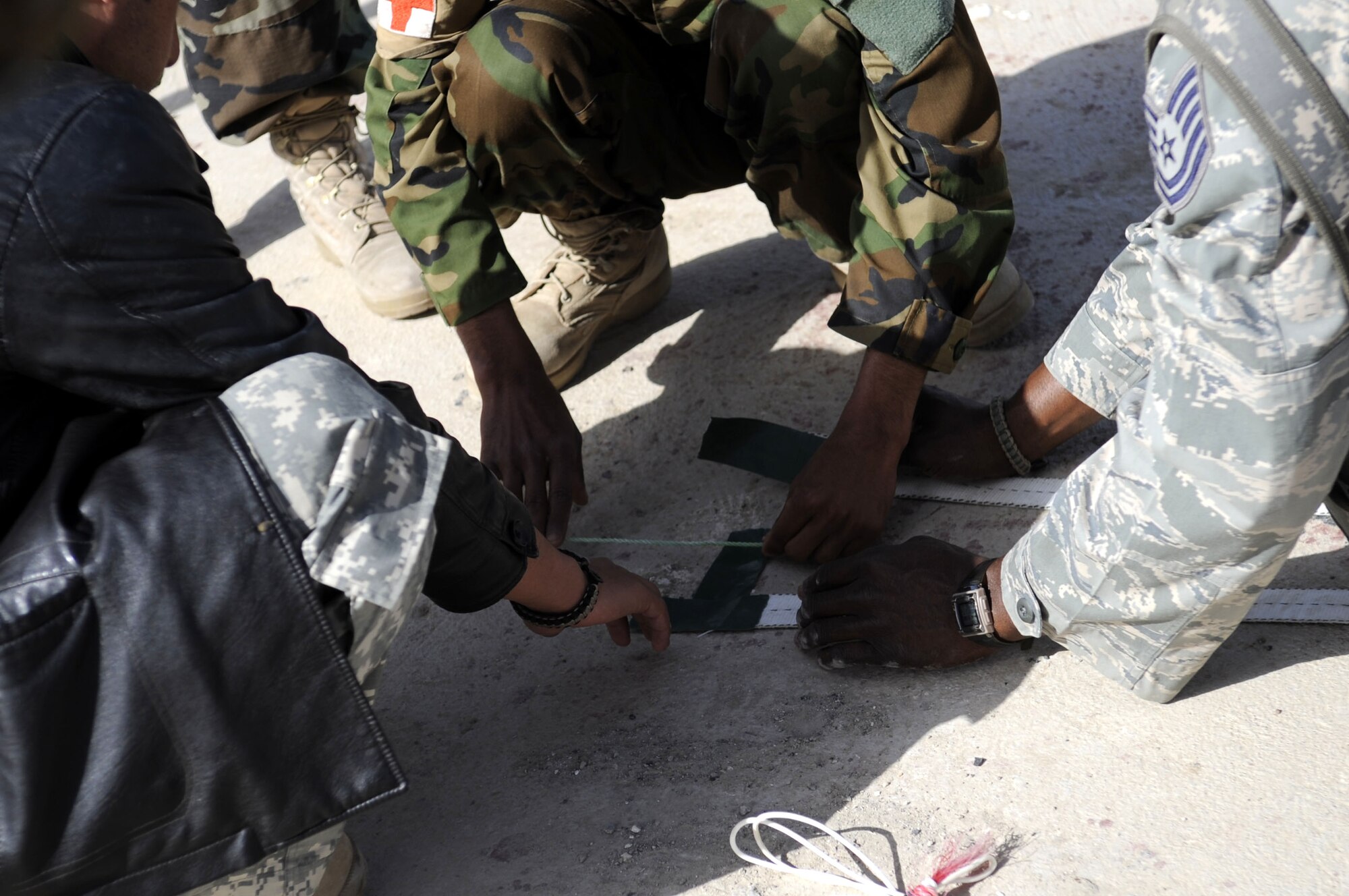 Technical Sergeant Vernon Jones, DCST—Task Force Phoenix medical advisor to the Kandahar Regional Military Hospital, assists members of the Afghan National Army as they construct a volleyball court to increase morale for their soldiers, March 1, at Camp Hero, Kandahar Airfield, Afghanistan. (U.S. Air Force photo by Senior Airman Nancy Hooks/Released)
