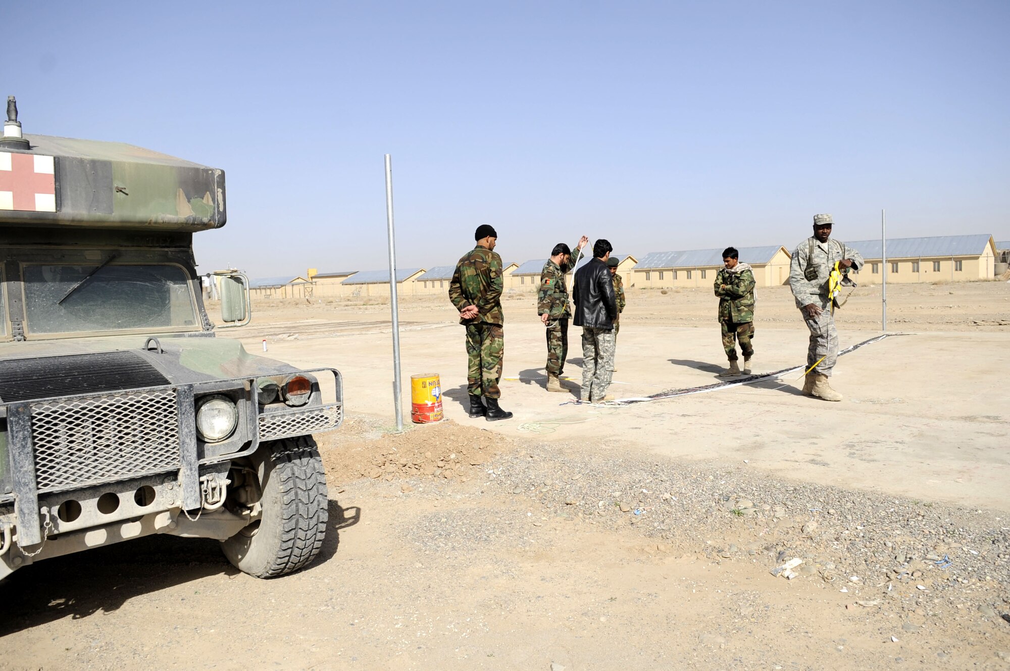 Technical Sergeant Vernon Jones, DCST—Task Force Phoenix medical advisor to the Kandahar Regional Military Hospital, assists members of the Afghan National Army as they construct a volleyball court to increase morale for their soldiers, March 1, at Camp Hero, Kandahar Airfield, Afghanistan. (U.S. Air Force photo by Senior Airman Nancy Hooks/Released)
