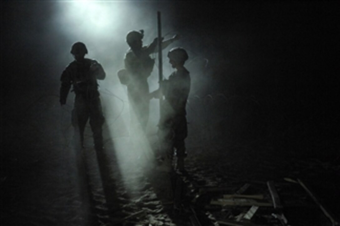 U.S. Army soldiers with Bear Troop, 8th Squadron, 1st Cavalry Regiment fortify an Afghan Highway Police checkpoint in Robat, Afghanistan, by placing razor wire around the perimeter on March 19, 2010.  