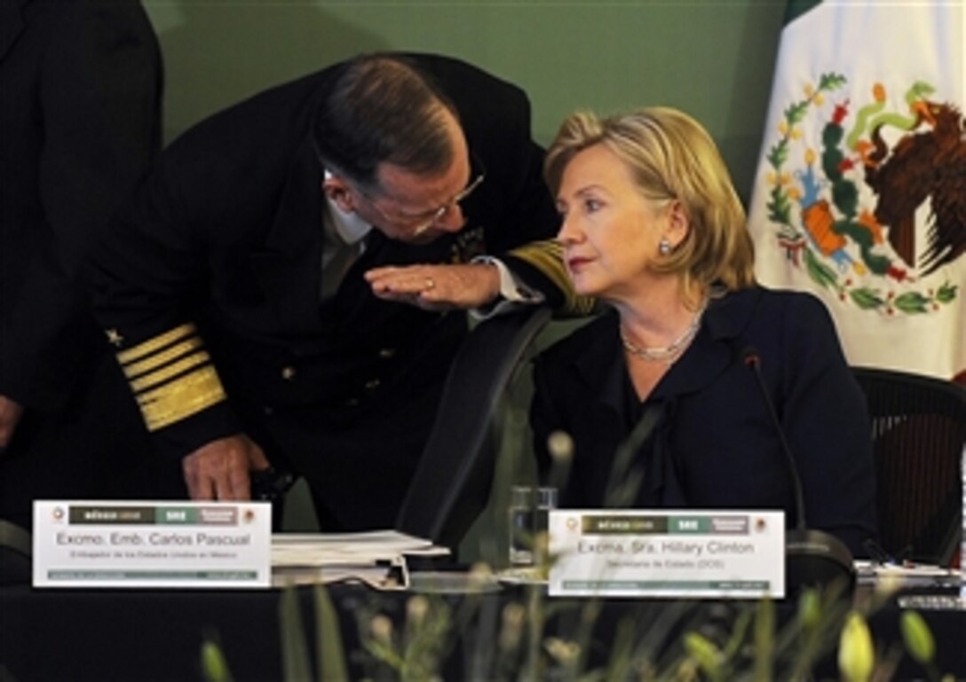 Chairman of the Joint Chiefs of Staff Adm. Mike Mullen and Secretary of State Hillary Clinton talk to one another during the Merida Initiative Plenary, which focuses on helping the Mexican government fight drug-trafficking cartels and other security threats.  