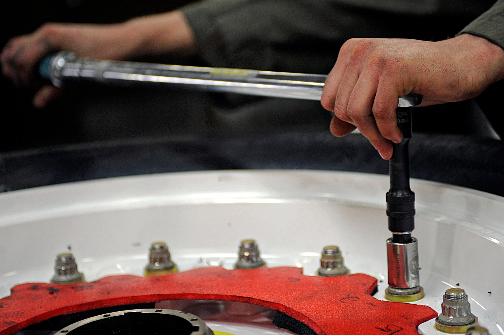 ELLSWORTH AIR FORCE BASE, S.D. -- Senior Airman Caleb Christian, 28th Maintenance Squadron repair and reclamation journeyman, tightens bolts on a tire using an impact wrench, March 24. Repair and reclamation personnel use a one-man-build stand to hold the tire in place while they repair it. (U.S. Air Force photo/Airman 1st Class Matthew Flynn)