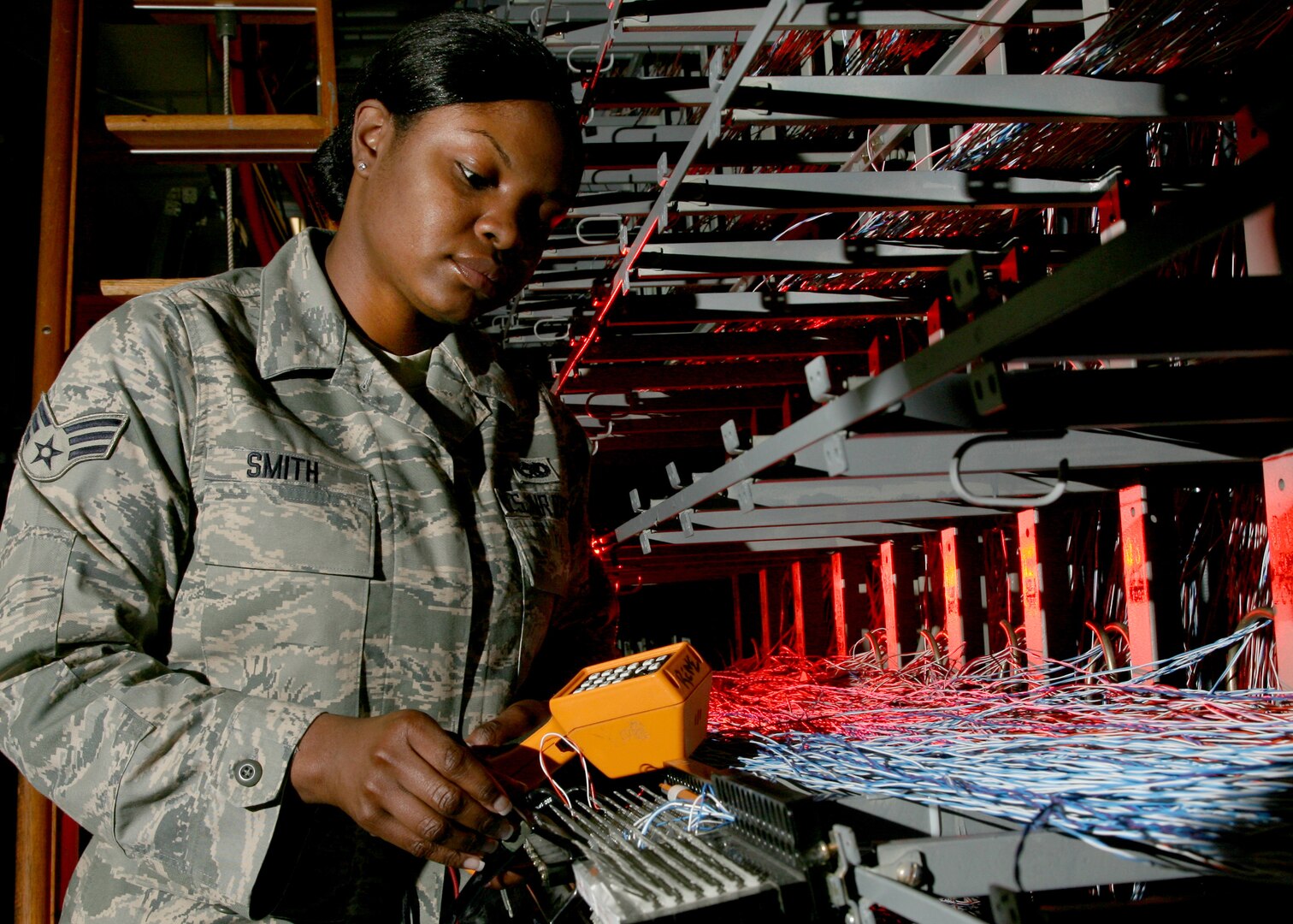 Senior Airman Shinikqua Smith, 802nd Communications Squadron, tests cable before rewiring a circuit in the voice networks switch. (U.S. Air Force photo/Robbin Cresswell)