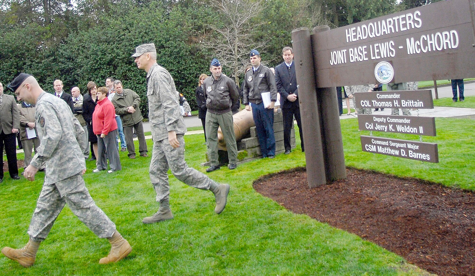 Army Col. Thomas Brittain, left, and Air Force Col. Kenny Weldon walk away from the new headquarters sign after a ceremony marking attainment of initial operational capability for Joint Base Lewis-McChord, Wash., Feb. 1, 2010. The joint installation comprises the former Fort Lewis and McChord Air Force Base. (U.S. Army photo/Ingrid Barrentine)