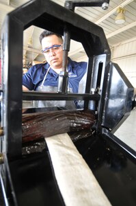 Harmin Aguilera, a Randolph Air Force Base Hazardous Waste technician, wrings shop waste cloths to salvage waste oil for proper disposal.  (U.S. Air Force photo by Steve White)