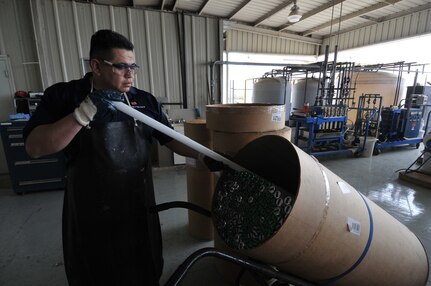 Harmin Aguilera, a Randolph Air Force Base Hazardous Waste technician, fills a container with burnt out flourescent bulbs. (U.S. Air Force Photo by Steve White)
