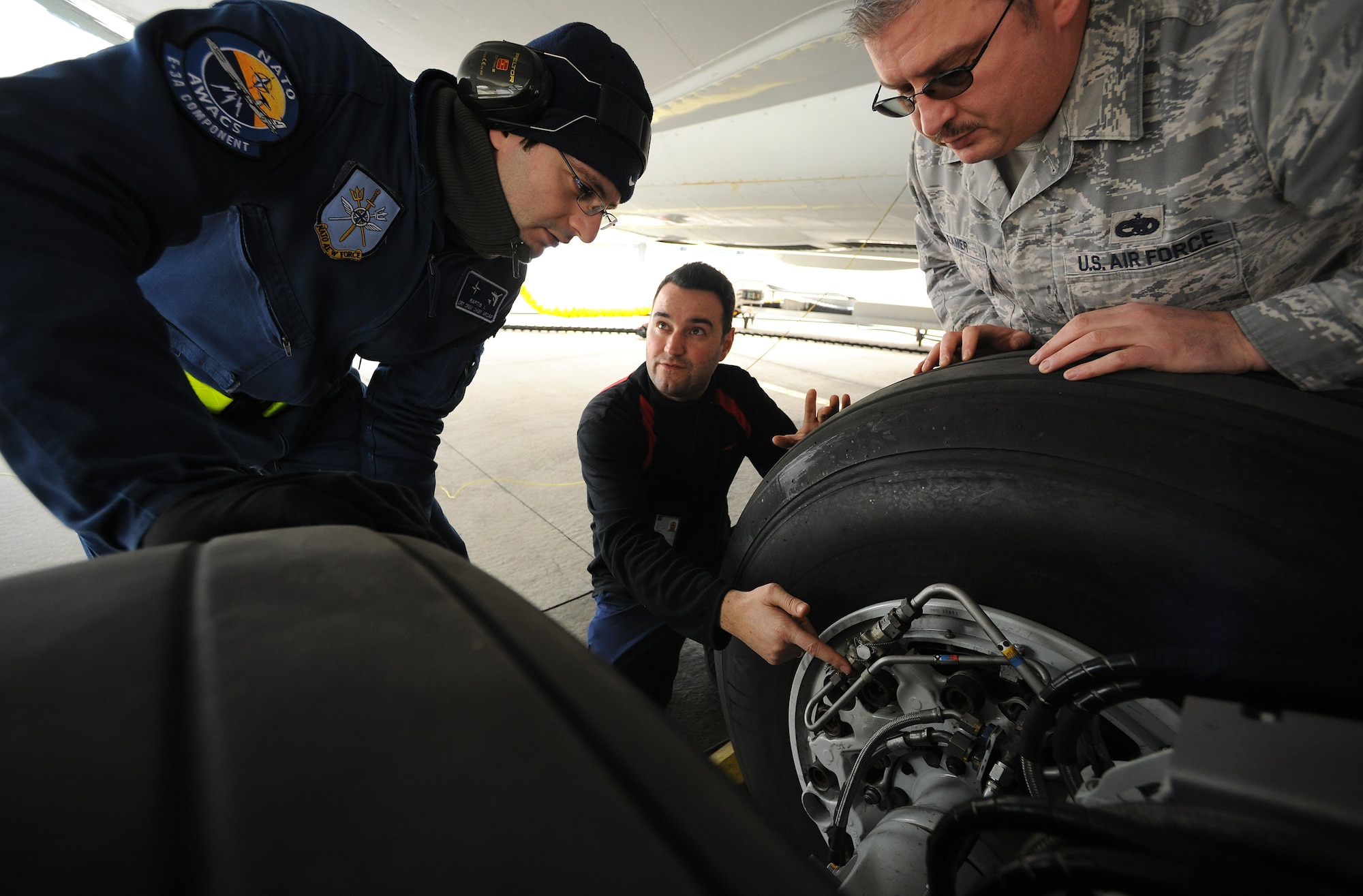 NATO AIR BASE GEILENKIRCHEN, Germany – German contractor Lars Boemer, center, NATO E-3A Airborne Early Warning and Control force component E-3A Sentry crew chief, explains the proper procedures for inspecting the landing gear of an E-3A to Greek air force Master Sgt. Ilias Raptis, left, and Tech. Sgt. Richey Leamer, NATO AWACS component E-3A crew chiefs, March 19. The E-3A component is made of 15 nations and is NATO’s only multinational operational flying unit. (U.S. Air Force photo/Senior Airman Nathanael Callon)