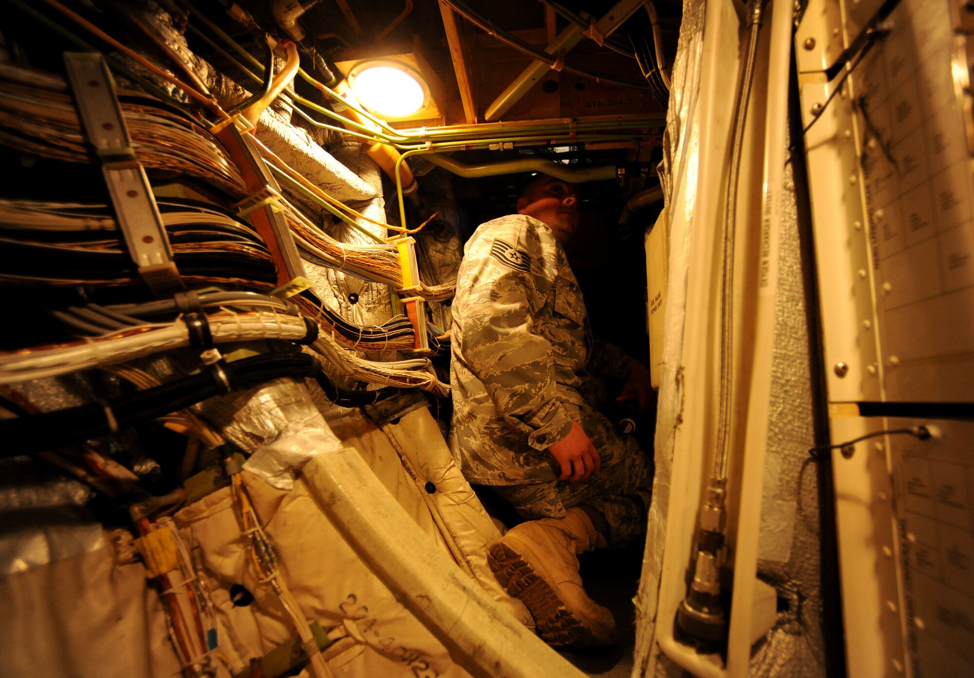 NATO AIR BASE GEILENKIRCHEN, Germany – Tech. Sgt. Garrett Blake, NATO E-3A Airborne Early Warning and Control force component logistics wing aircraft phase technician, squeezes out from under the cockpit of an E-3A Sentry after inspecting the flight control cables March 19. The E-3A is a four-engine, modified Boeing 707-320 aircraft that provides all-weather surveillance, command, control and communications needed by the commanders of NATO air forces. (U.S. Air Force photo/Senior Airman Nathanael Callon)