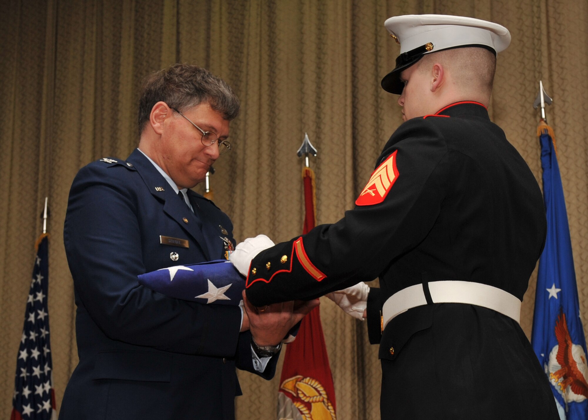 During his retirement ceremony on Mar. 18, 2010, U.S. Air Force Colonel Robert G. Stiegel accepts the U.S. flag that flew over RAF Molesworth in his honor from U.S. Marine Corps Sgt. Marcus A. Voshell.   (Photo by U.S. Air Force Staff Sgt. Javier Cruz)