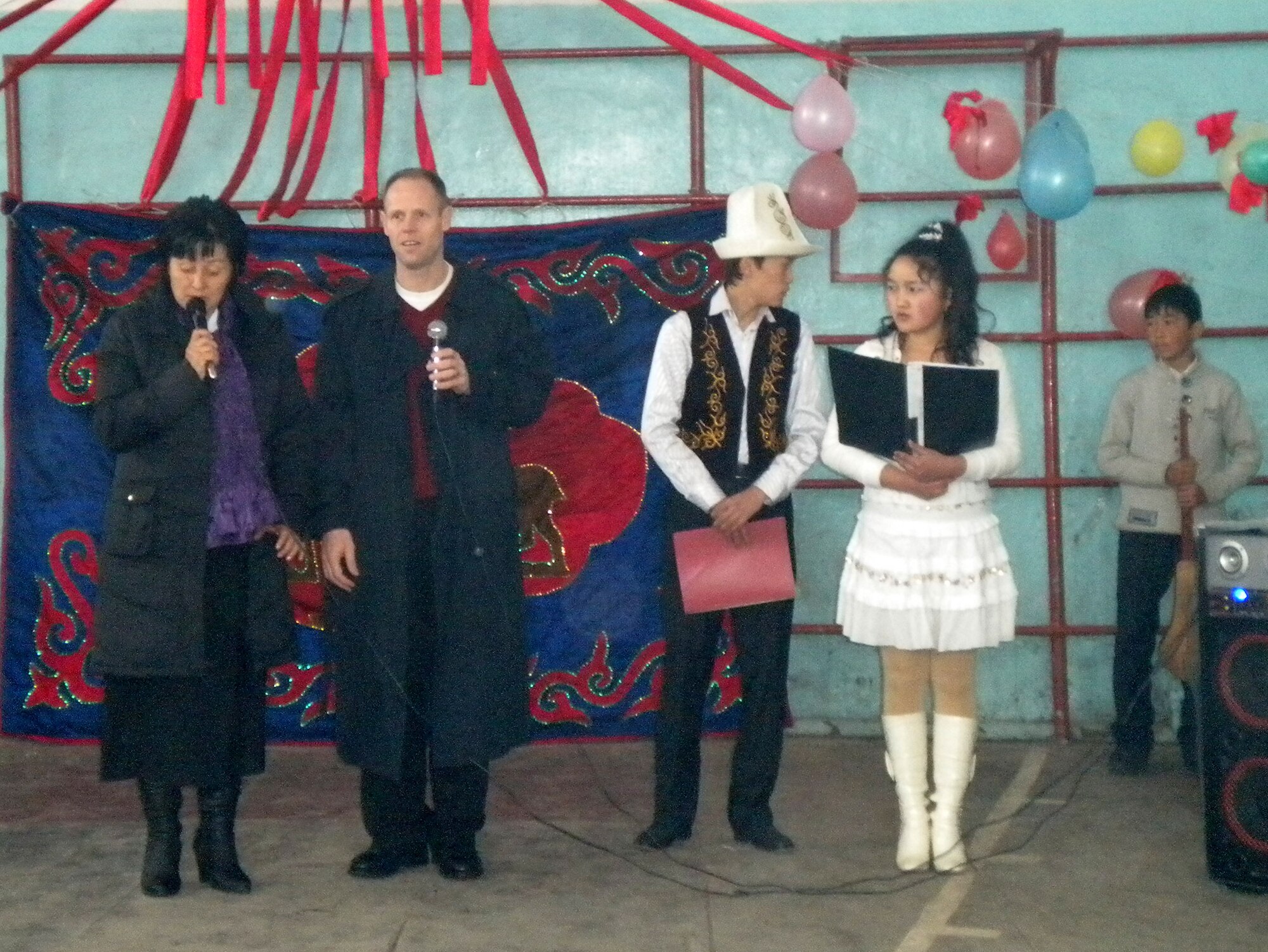 Col. Blaine Holt, director of the Transit Center of Manas, addresses the citizens of Manas Village March 21, 2010, at Ak Jhol School in commemoration of Nooruz, a spring holiday celebrated in Kyrgyzstan, while Valentina Turabekova translates. (U.S. Air Force photo/Chief Master Sgt. James Dowell/released)