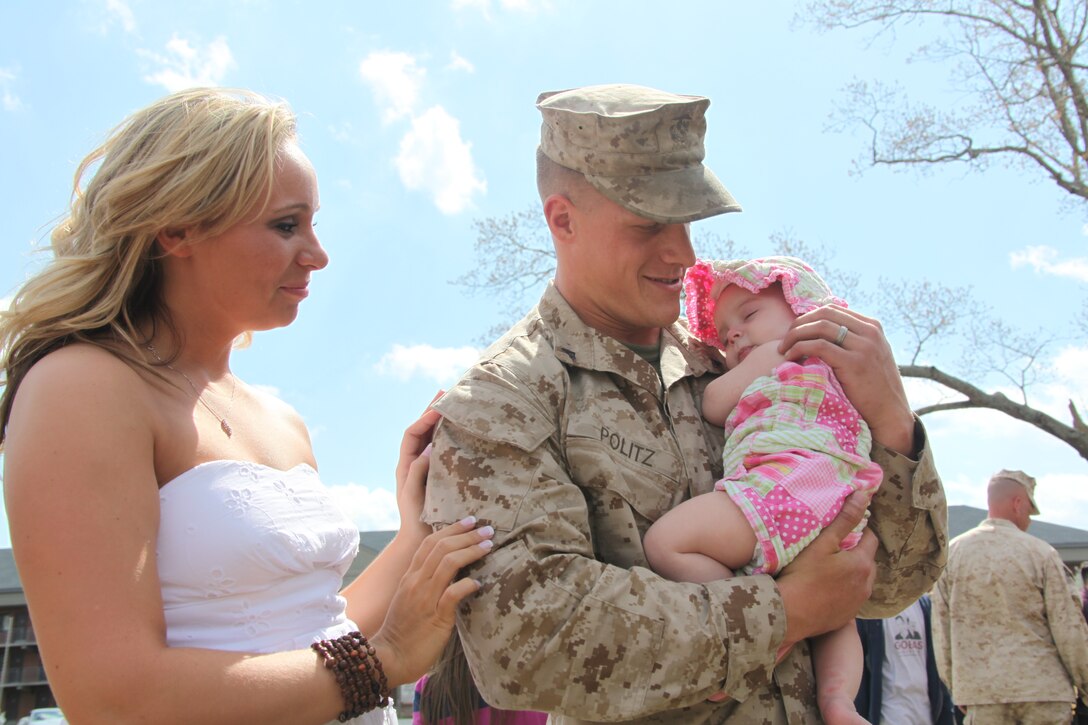 Lance Cpl. Ryan L. Politz, a mobile facility technician with Marine Aviation Logistics Squadron 40, hugs his daughter, Lorelai, at the MALS-40 homecoming, March 26. Politz’s wife, Sinead, pictured left, and their daughter were one of many families anxiously awaiting the arrival of their leathernecks.