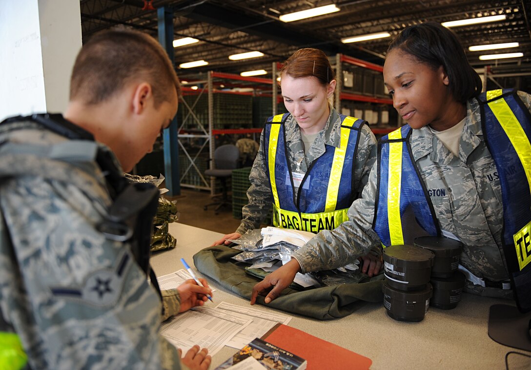 LANGLEY AIR FORCE BASE, Va. -- Airmen 1st Class Courtney Runyon and Tiana Wadlington, 633d Logistics and Readiness Squadron, process an Airman through the mobility equipment issue portion of the personnel deployment function line during a Phase I Operational Readiness Exercise here March 26. The 633 LRS held an internal competition to see which two-person team could process personnel the quickest, and Airmen Runyon and Wadlington were in the lead with a time of one minute and 36 seconds. (U.S. Air Force photo/Airman Rebecca Montez)