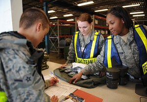 LANGLEY AIR FORCE BASE, Va. -- Airmen 1st Class Courtney Runyon and Tiana Wadlington, 633d Logistics and Readiness Squadron, process an Airman through the mobility equipment issue portion of the personnel deployment function line during a Phase I Operational Readiness Exercise here March 26. The 633 LRS held an internal competition to see which two-person team could process personnel the quickest, and Airmen Runyon and Wadlington were in the lead with a time of one minute and 36 seconds. (U.S. Air Force photo/Airman Rebecca Montez)