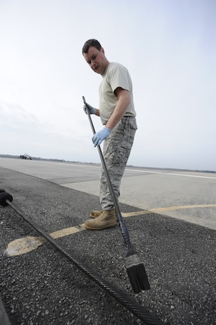 U.S. Air Force Staff Sgt. Lewis Paine applies a biodegradable lubricant on a pendent cable on the runway at Joint Base Charleston, S.C., March 25, 2010. The cable is inspected and maintained once a month and is designed to help stop aircraft equipped with an arresting hook while landing. Sergeant Paine is a power production technician with the 628th Civil Engineer Squadron. (U.S. Air Force photo by James M. Bowman/released)