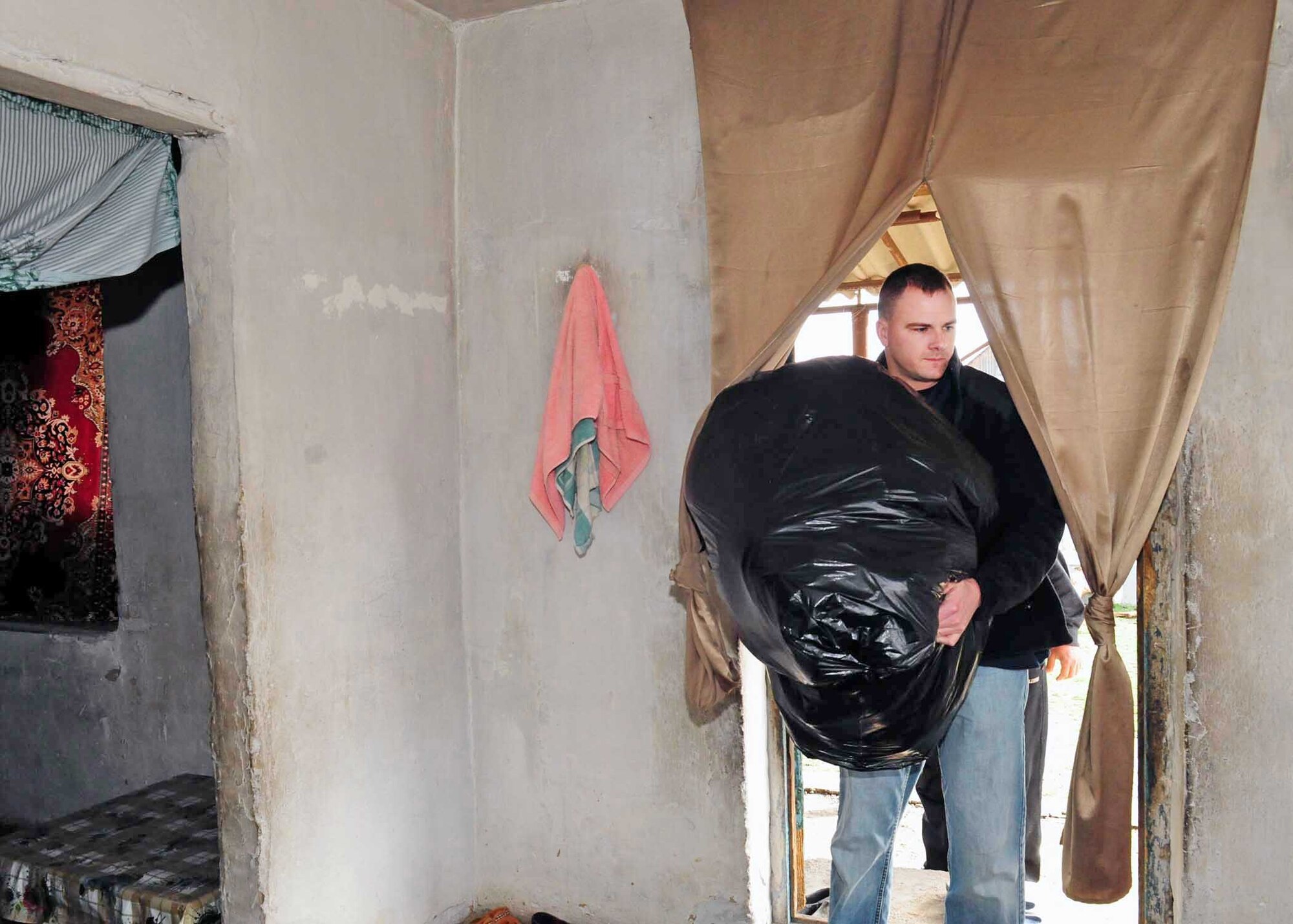 Tech. Sgt. Jake Mayo brings humanitarian assistance items collected from stateside bases and friends into the home of a family March 18, 2010, in Manas Village, Kyrgyzstan. Sergeant Mayo is the 376th Expeditionary Logistics Readiness Squadron vehicle maintenance NCO in charge deployed from the Air National Guard in Birmingham, Ala. (U.S. Air Force photo/Staff Sgt. Carolyn Viss)