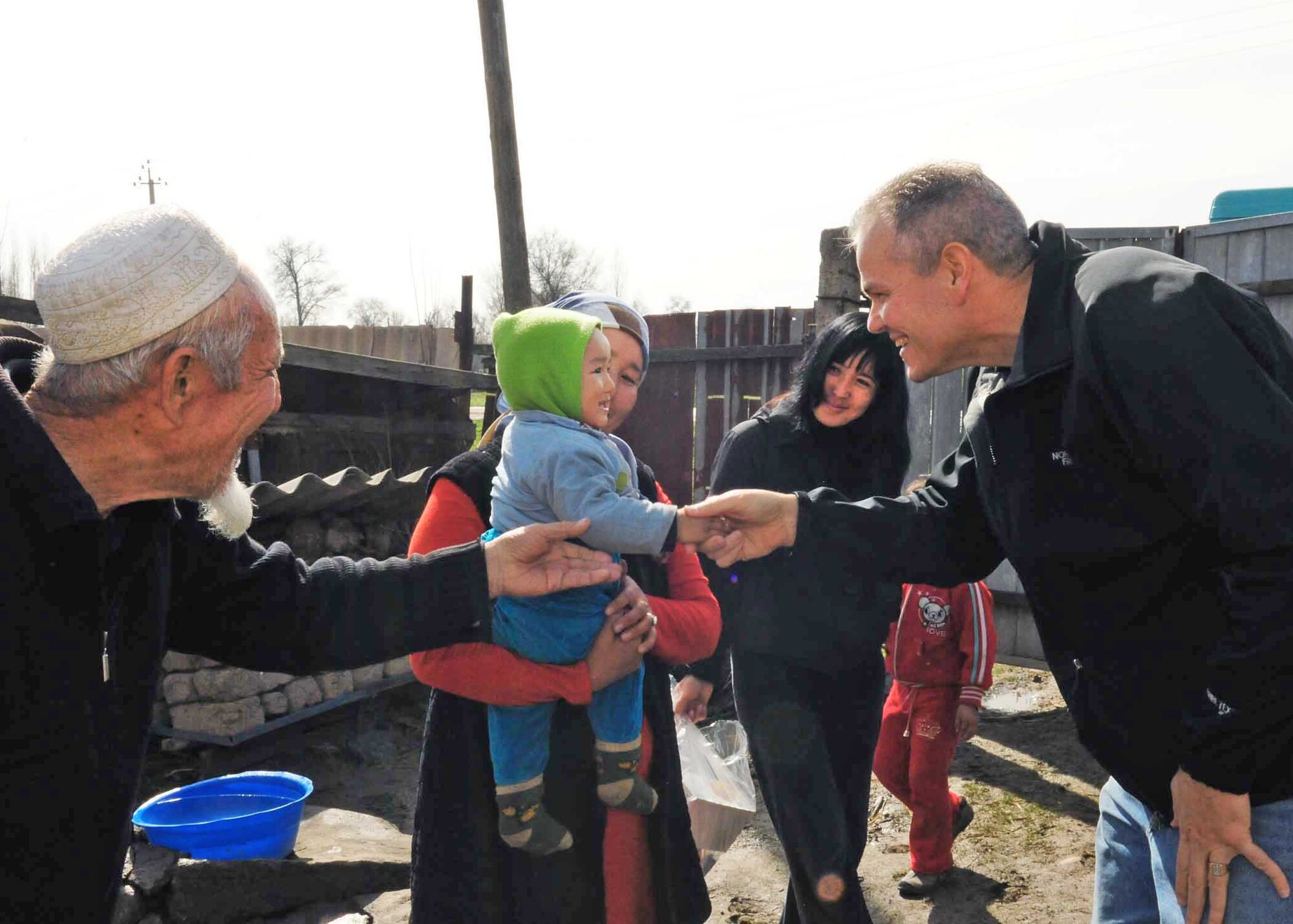 Lt. Col. Rex Vanderwood shakes the hand of a little boy after delivering humanitarian assistance items collected from stateside bases and friends to a family March 18, 2010, in Manas Village, Kyrgyzstan. Colonel Vanderwood is the 376th Expeditionary Mission Support Group deputy commander. (U.S. Air Force photo/Staff Sgt. Carolyn Viss)