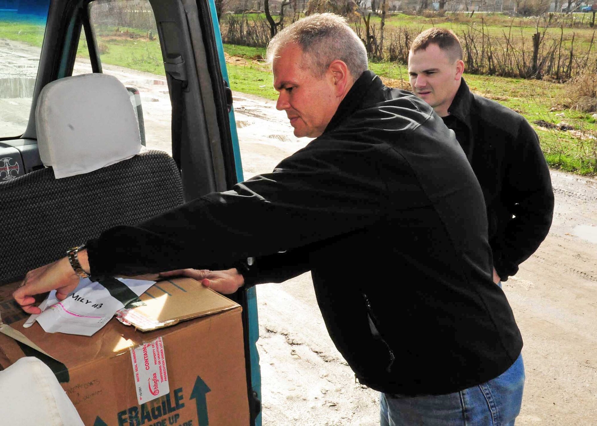Lt. Col. Rex Vanderwood and Tech. Sgt. Jake Mayo unload a box of humanitarian assistance items collected from stateside bases and friends to distribute to families March 18, 2010, in Manas Village, Kyrgyzstan. Colonel Vanderwood is the 376th Expeditionary Mission Support Group deputy commander. Sergeant Mayo is the 376th Expeditionary Logistics Readiness Squadron vehicle maintenance NCO in charge deployed from the Air National Guard in Birmingham, Ala. (U.S. Air Force photo/Staff Sgt. Carolyn Viss)