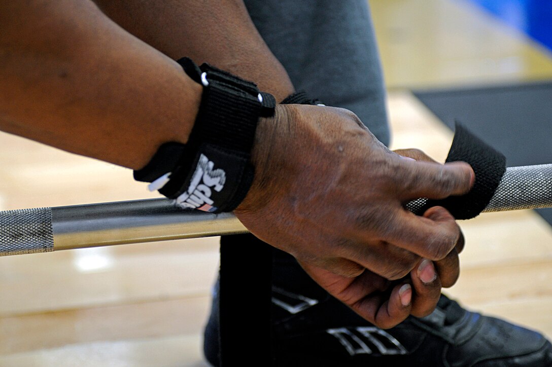 ELLSWORTH AIR FORCE BASE, S.D. -- Staff Sgt. Tywone Weston, 28th Maintenance Squadron jet engine mechanic, attaches straps to a weight lifting bar during the Bellamy Fitness Center powerhouse competition, March 25. Sergeant Weston is using the straps to help him maintain a better grip during his lift.. (U.S. Air Force photo/Airman 1st Class Matthew Flynn) 