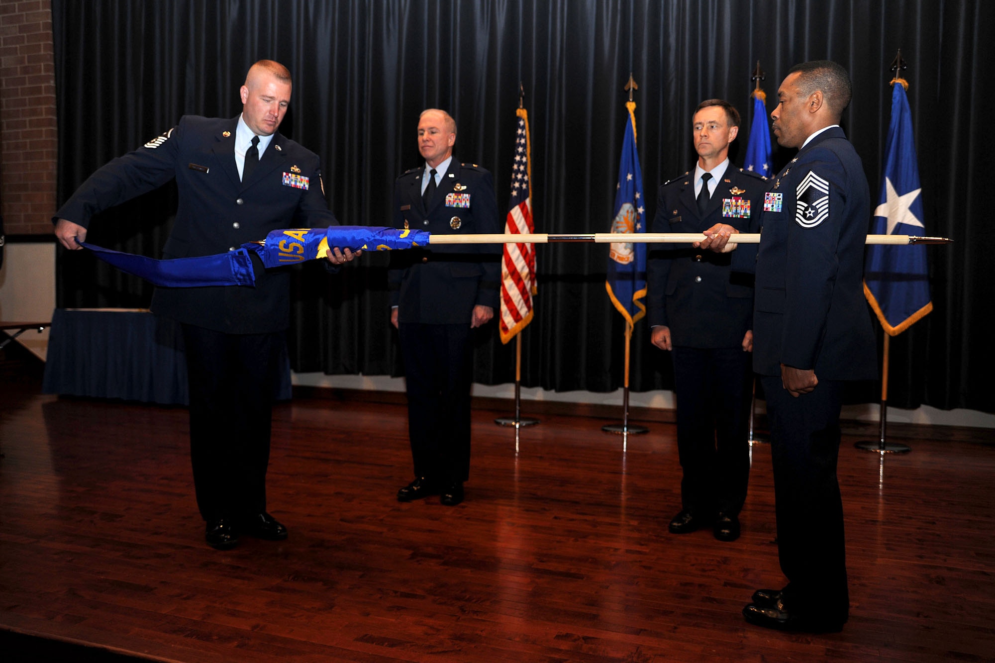 Master Sgt. Ed Malkowski, U.S. Air Force Expeditionary Center First Sergeant, unveils the guidon of the newly activated 422nd Joint Tactics Squadron March 26 held by Chief Master Sgt. Leighton Chang, Chief of Expeditionary Operations School, as Brig. Gen. Richard Devereaux, Expeditionary Center commander (left), and Col. Mark Ellis, Expeditionary Operations School commandant, look on.  The 422nd Joint Tactics Squadron, formerly the Expeditionary Center?s Tactics, Techniques and Procedures Division, is tasked with collecting information from combat zones and distributing that information to expeditionary combat support Airmen both in training and serving in forward areas. (U.S. Air Force Photo/Staff Sgt. Nathan G. Bevier/Released) 