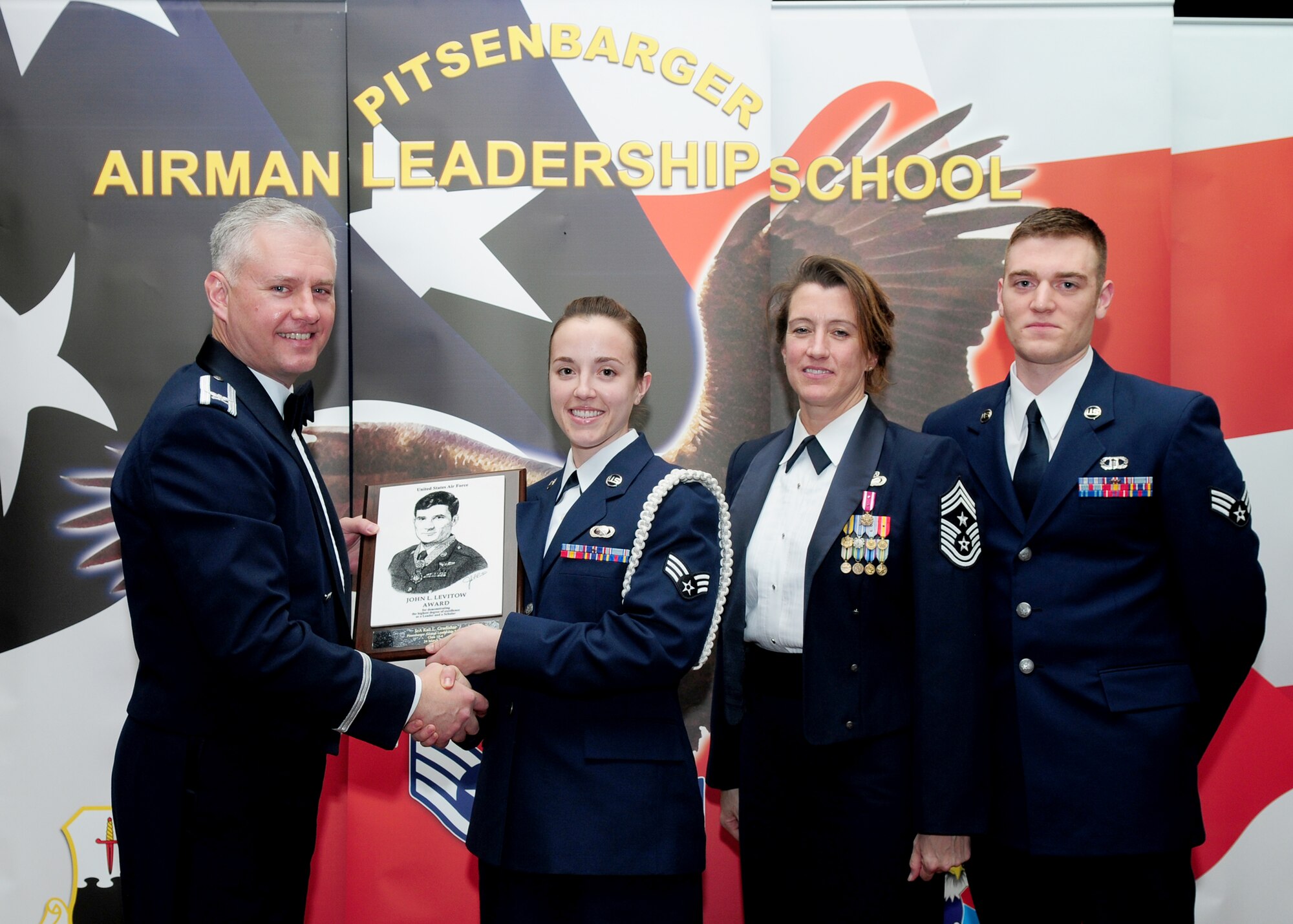 SPANGDAHLEM AIR BASE, Germany -- Senior Airman Kali Gradishar, 52nd Fighter Wing Public Affairs journalist, accepts the John L. Levitow Award from Col. Kevin Anderson, 52nd FW vice commander; Chief Master Sgt. Sandra Miller, 52nd FW command chief; and Senior Airman Steven Ott, previous John L. Levitow award recipient, during the Pitsenbarger Airman Leadership School Class 10-4 graduation in Club Eifel March 24. The John L. Levitow award is the highest level award an Airman can receive upon completion of ALS. (U.S. Air Force photo/Staff Sgt. Heather M. Norris)