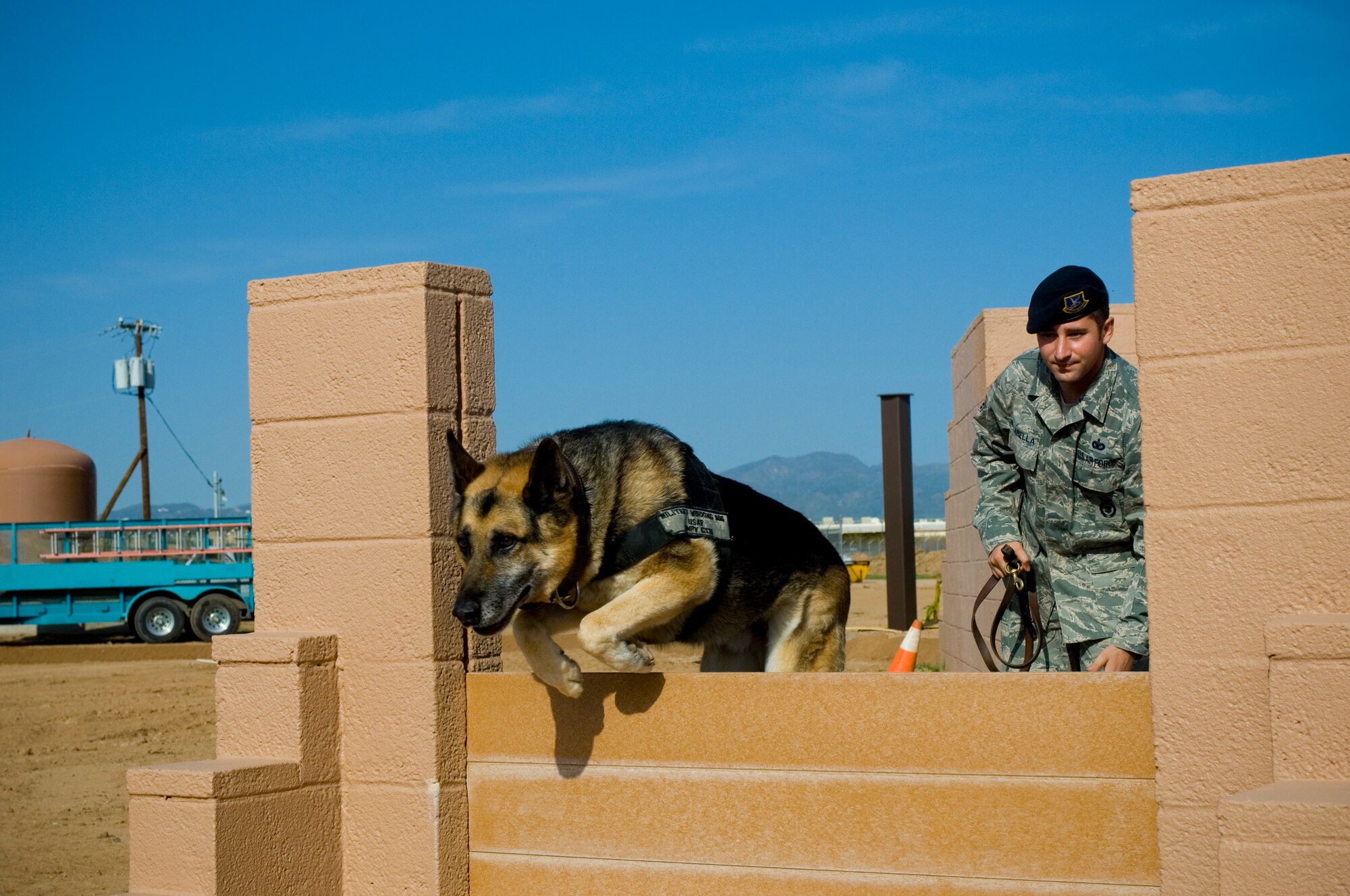 Staff Sgt. John Pillarella, 56th Security Forces military working dog kennel master, commands Jampy to leap over a barrier during his final run of the obstacle course at the Military Working Dog kennels, Luke Air Force Base, Ariz., March 25, 2010. Jampy is one of three dogs due to be medically retired April 6, 2010 due to old age. (U.S. Air Force Photo by Staff Sgt. Jason Colbert)

