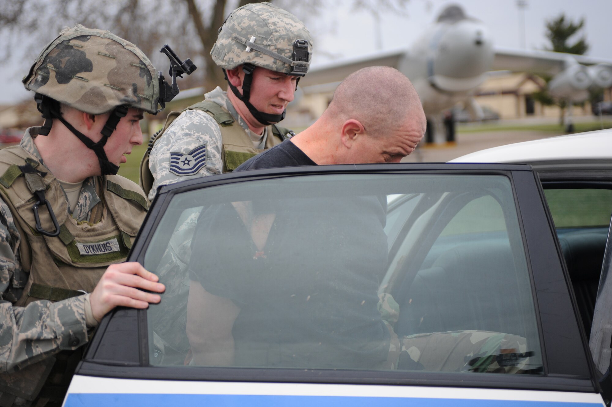 WHITEMAN AIR FORCE BASE, Mo., -- Senior Airman Anthony Dykhuis and Tech. Sgt. Jonathon Huber, 509th Security Forces Squadron, put Lt. Col. Daniel Semsel, 509th Mission Support Squadron deputy commander, into the back of the squad car after being apprehended during the active shooter exercise here March 24, 2010. The 509th SFS, and many others throughout the Air Force are training to deal with these types of threats from within. Hoping to reduce the number of casualties if such situations occur, a quick and effective response was the goal of the training exercise. (U.S. Air Force photo/Staff Sgt. Jason Huddleston)  (Released)