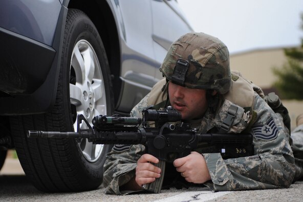 WHITEMAN AIR FORCE BASE, Mo., -- Tech. Sgt. Jason Birch, 509th Security Forces Squadron takes cover behind a vehicle as he watches the deployment center for any suspicious people exiting the building, during the active shooter exercise here March 24, 2010. The 509th SFS, and many others throughout the Air Force are training to deal with these types of threats from within. Hoping to reduce the number of casualties if such situations occur, a quick and effective response was the goal of the training exercise. (U.S. Air Force photo/Staff Sgt. Jason Huddleston)  (Released)