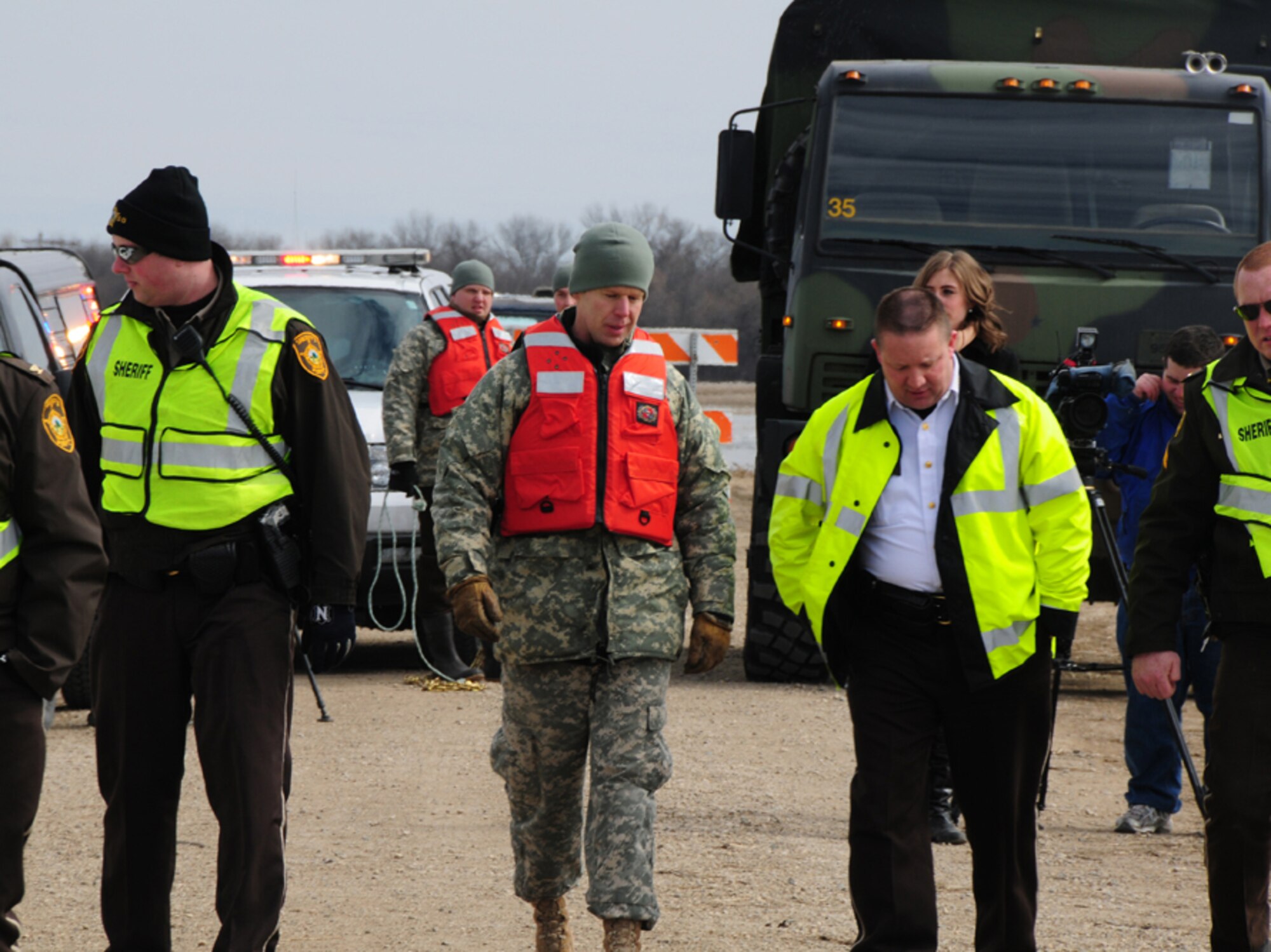Staff Sgt. Brent Johnson, of Argusville, N.D., who serves with the North Dakota National Guard’s 815th Engineer Company quick response force (QRF) team, visits with Cass County Sheriff Paul Laney as they arrive on the scene of a stranded automobile in a washed out section of rural roadway March 25, west of Harwood, N.D. The recovery of the car from the washout is cooperative effort between members of the North Dakota National Guard and the Cass County Sherriff’s Office operating out of a tactical operations center in West Fargo, N.D. The recovery was carried out by N.D. National Guard members of a quick response force (QRF) team staging out of the Harwood, N.D., Community Center. (DoD photo by Senior Master Sgt. David H. Lipp) (Released)