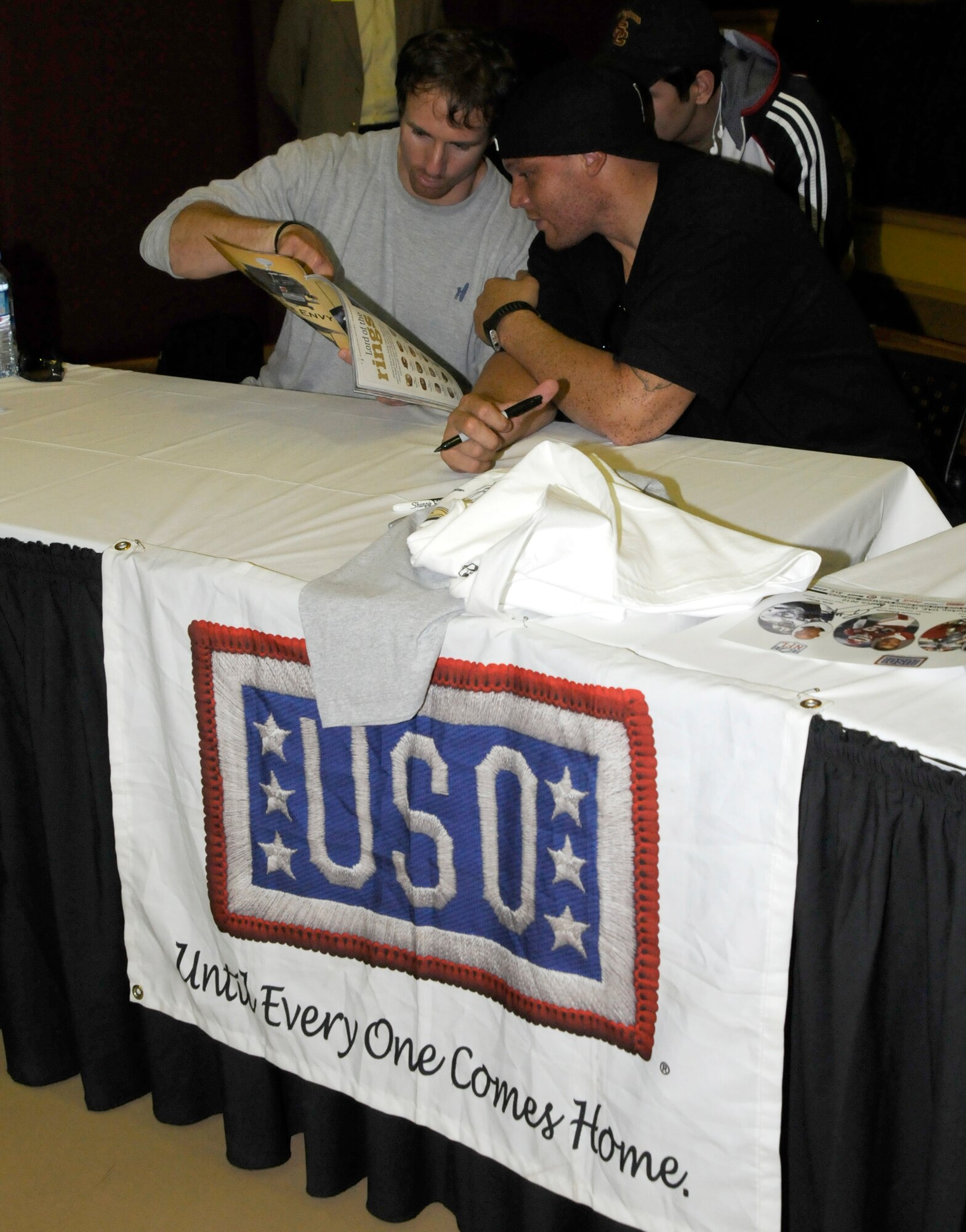 (Left to right) Drew Brees, quarterback for the New Orleans Saints, and Billy Miller, tight end for the New Orleans Saints, take a look at a magazine tribute to their 2010 Super Bowl win Wednesday, March 24, 2010 during the United Service Organizations tour at Incirlik Air Base, Turkey. Brees and Miller were joined by Donnie Edwards, former National Football League linebacker, for a  visit to Incirlik for three days to tour the base, meet with Airmen and contribute to the moral at Incirlik. (U.S. Air Force photo/Airman 1st Class Amber Ashcraft)