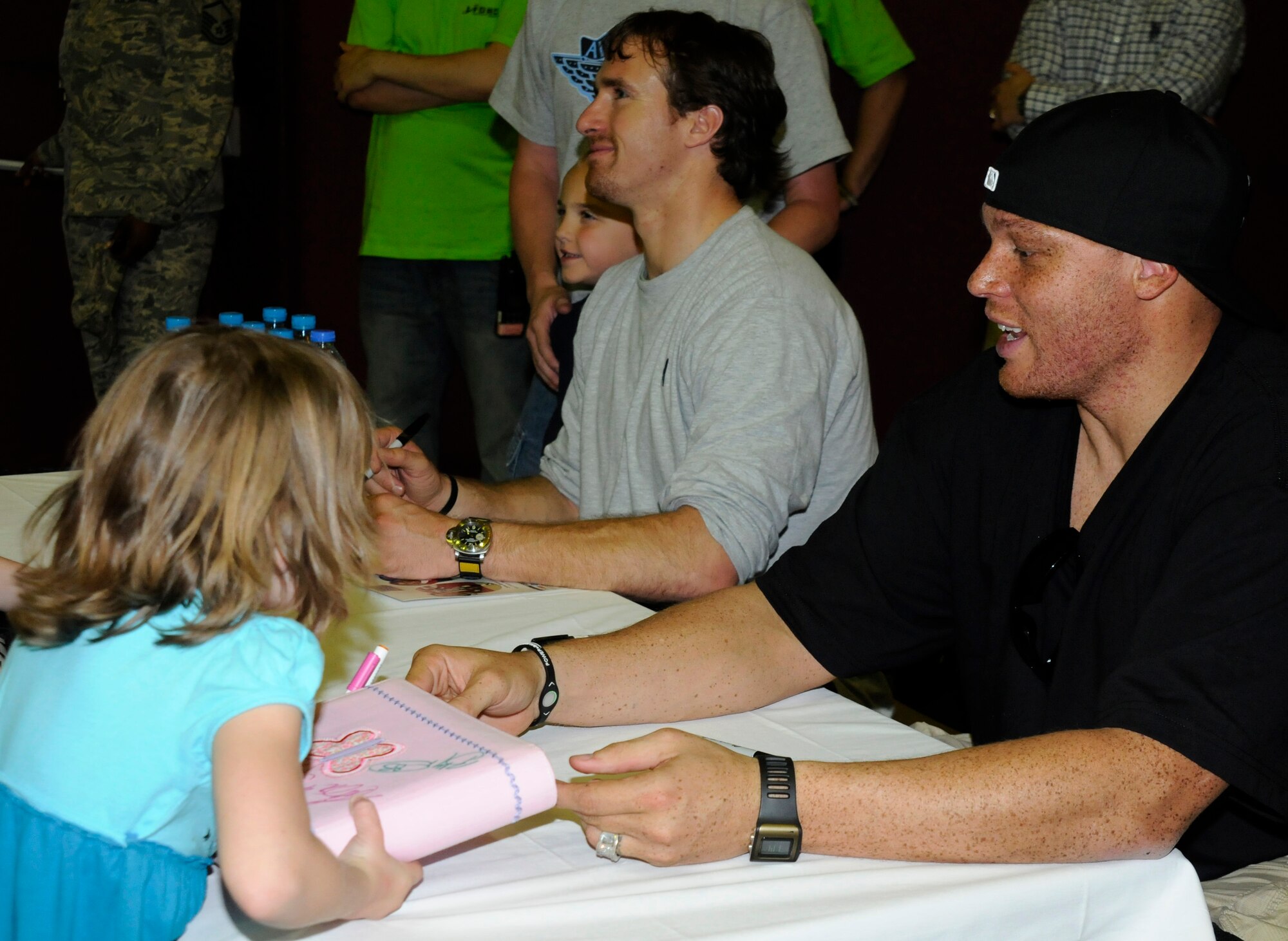 (Left to right) Drew Brees, quarterback for the New Orleans Saints, poses for a picture, while Billy Miller, tight end for the New Orleans Saints, signs a child’s photo album Wednesday, March 24, 2010 during the United Service Organizations tour at Incirlik Air Base, Turkey. Brees and Miller were joined by Donnie Edwards, former National Football League linebacker, for a  visit to Incirlik for three days to tour the base, meet with Airmen and contribute to the moral at Incirlik. (U.S. Air Force photo/Airman 1st Class Amber Ashcraft)
