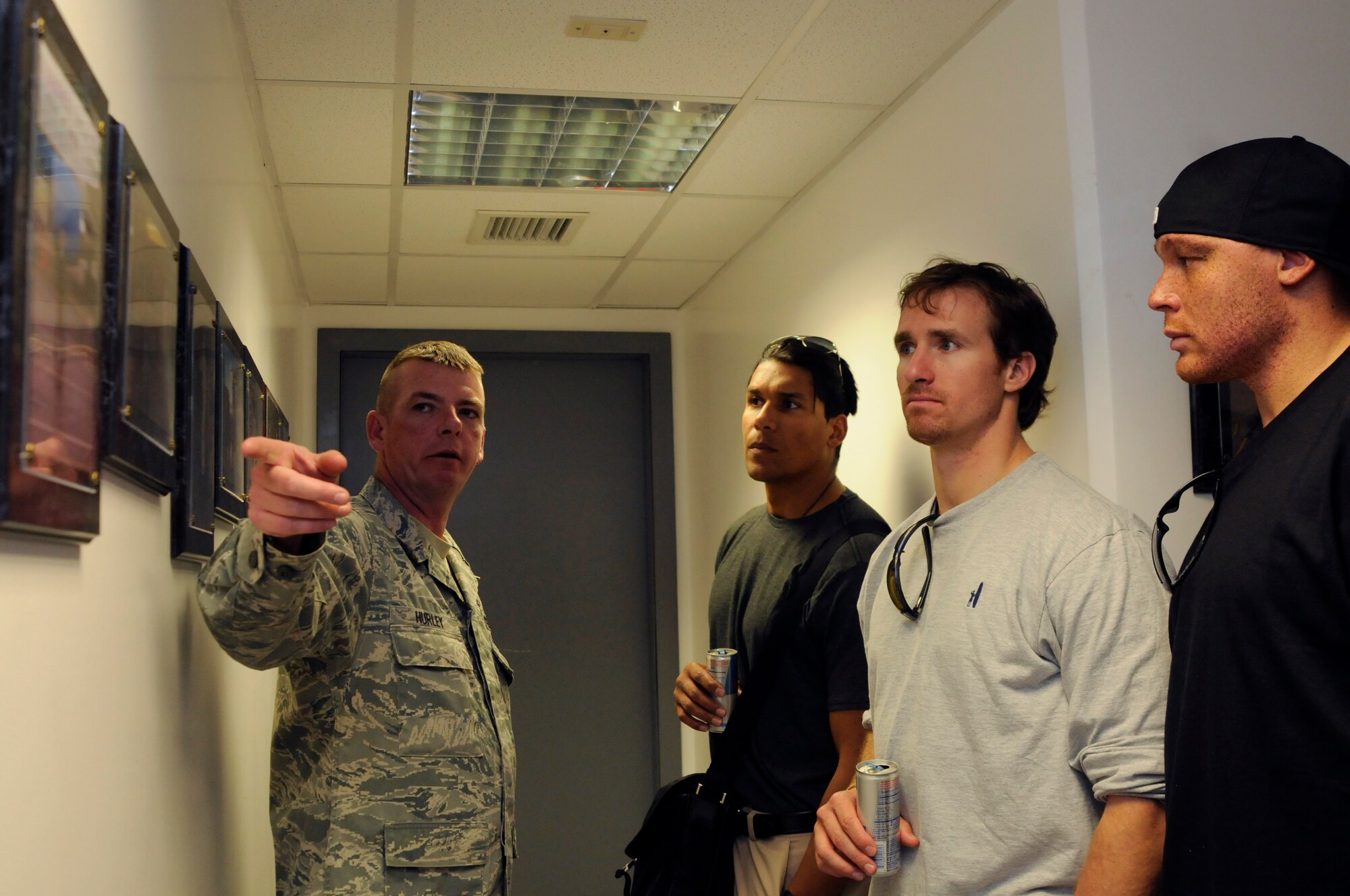 Senior Master Sgt. Jeffrey Hurley, 39 Civil Engineer Squadron chief enlisted manager, explains some of the photos in the hall of the Explosive Ordinance Disposal building Wednesday, March 24, 2010 to (from left to right) Donnie Edwards, former National Football League linebacker, Drew Brees, quarterback for the New Orleans Saints, and Billy Miller, tight end for the New Orleans Saints, during the United Service Organizations led tour at Incirlik Air Base, Turkey. The NFL stars visited Incirlik for three days to tour the base, meet with Airmen and contribute to the moral at the base. (U.S. Air Force photo/Airman 1st Class Amber Ashcraft)
