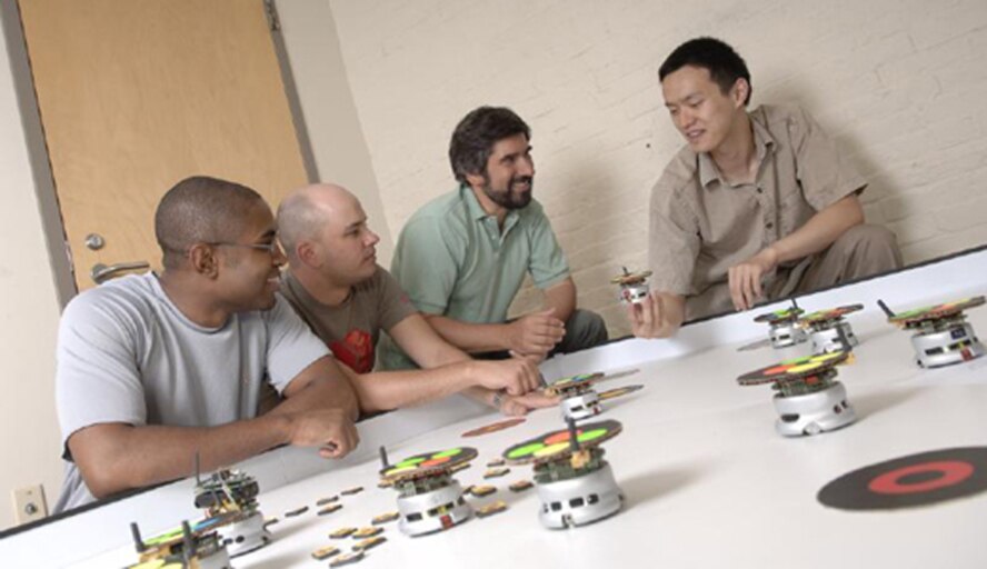 Boston University (BU) researchers discuss their approach to improving unmanned aerial vehicle (UAV) fleet automation.  Incorporating mission control and decision making algorithms 
to increase UAV self-sufficiency would save pilots significant effort. (Photo Credit:  Dr. David Castañón, BU)