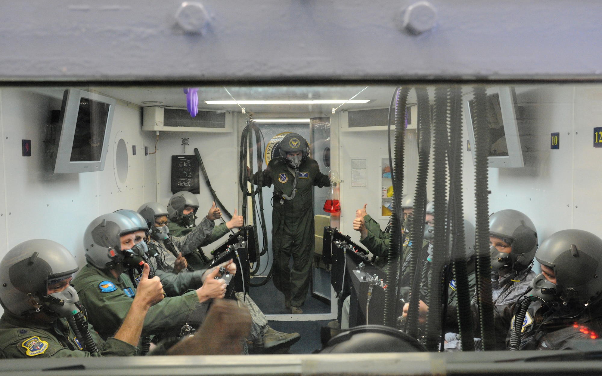 Major Daniel Gibson, 779th Aerospace Medicine Squadron aerospace and operational physiology training flight commander, observes as flight 1626 gives a thumbs up to indicate they are breathing normally and ready to proceed with training in the altitude chamber at Joint Base Andrews, Md., March 18, 2010. The physiology training flight trains aviators and special operations high-altitude parachutists how to recognize physiological stresses and human performance factors associated with military flying, and more importantly, how to overcome these challenges. (U.S. Air Force photo by Senior Airman Katie Spencer)