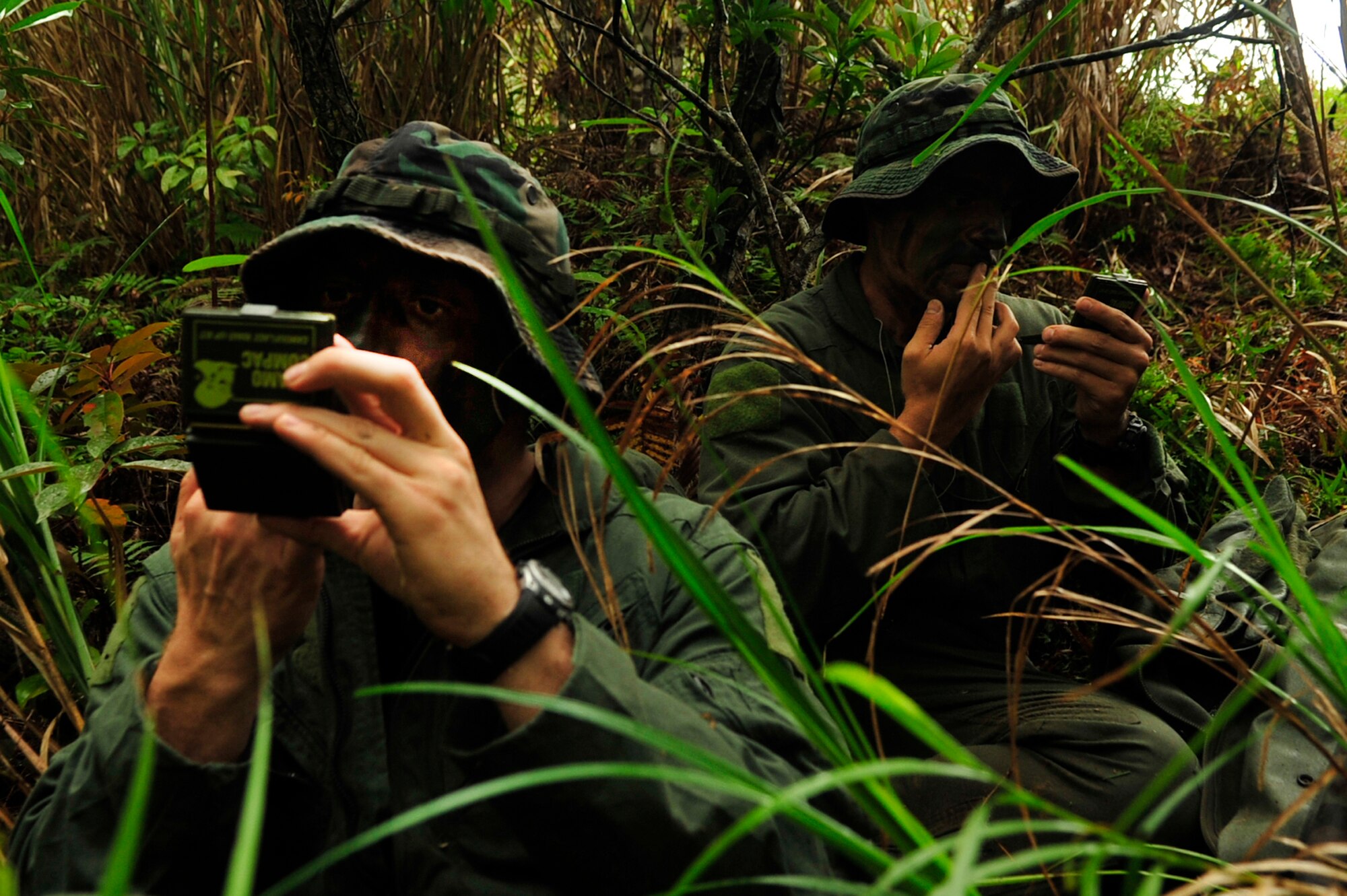 Capt. Aaron Wallace (left) and 1st Lt. Joseph Bisson (right), both pilots from the 909th Air Refueling Squadron, apply camouflage during an evasion scenario after a simulated KC-135 crash at Kadena Air Base, Japan, March 25. Members of the 909th ARS spent the afternoon training proper survival and evasion procedures. The training was part of Beverly High 10-02, a Local Operational Readiness Exercise designed to evaluate the readiness of Kadena Airmen. (U.S. Air Force photo/Senior Airman Amanda N. Grabiec)