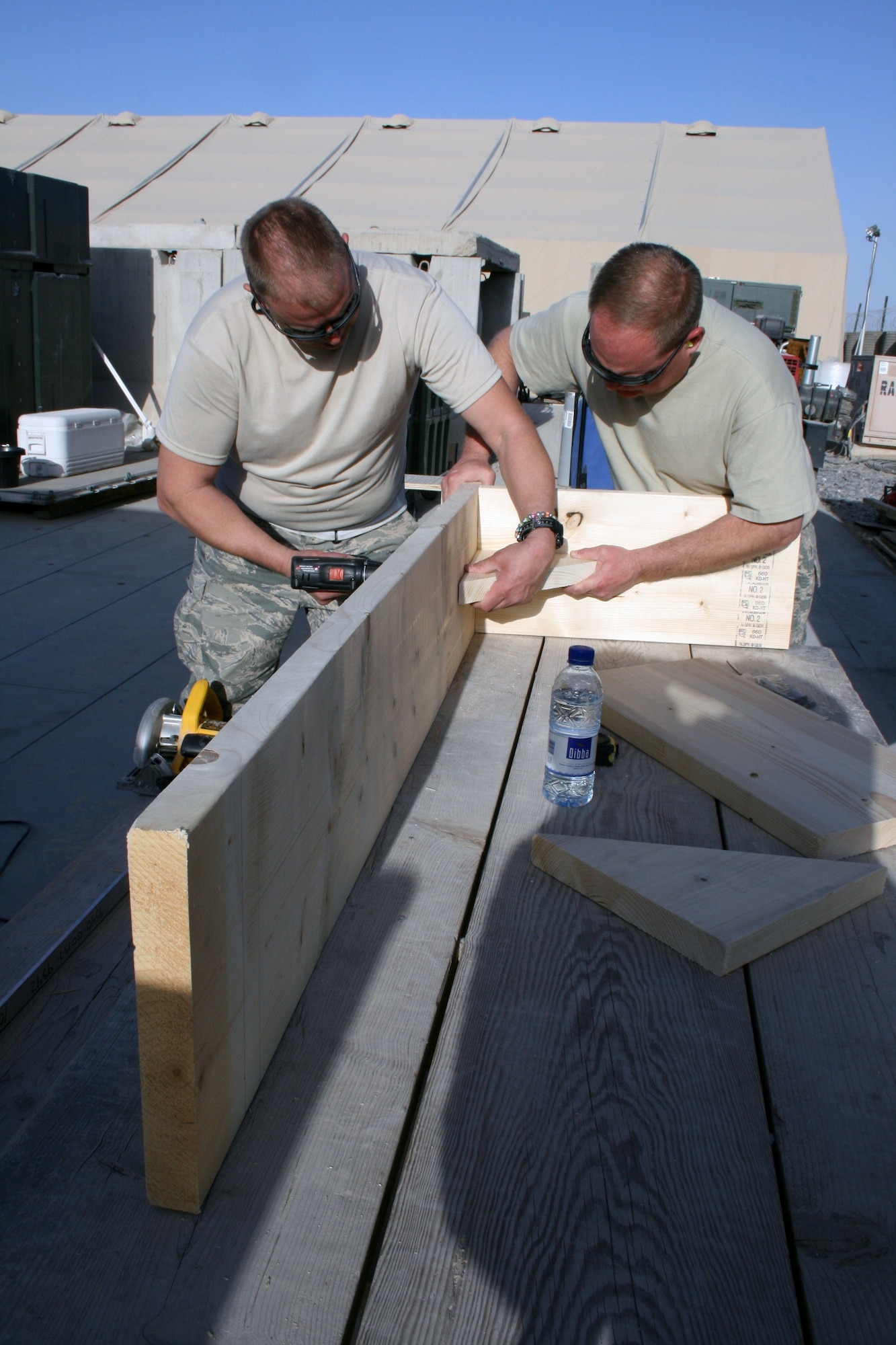 Two Airmen from the 451st Air Expeditionary Wing construct a bench at Kandahar Airfield, Afghanistan. Maintenance troops built tents, work tables and benches for use in doing the paperwork associated with maintaining their assigned aircraft, the A-10C. The Airmen are deployed from the Maryland Air National Guard in Baltimore. (U.S. Air Force photo by Tech. Sgt. David Speicher/Released)