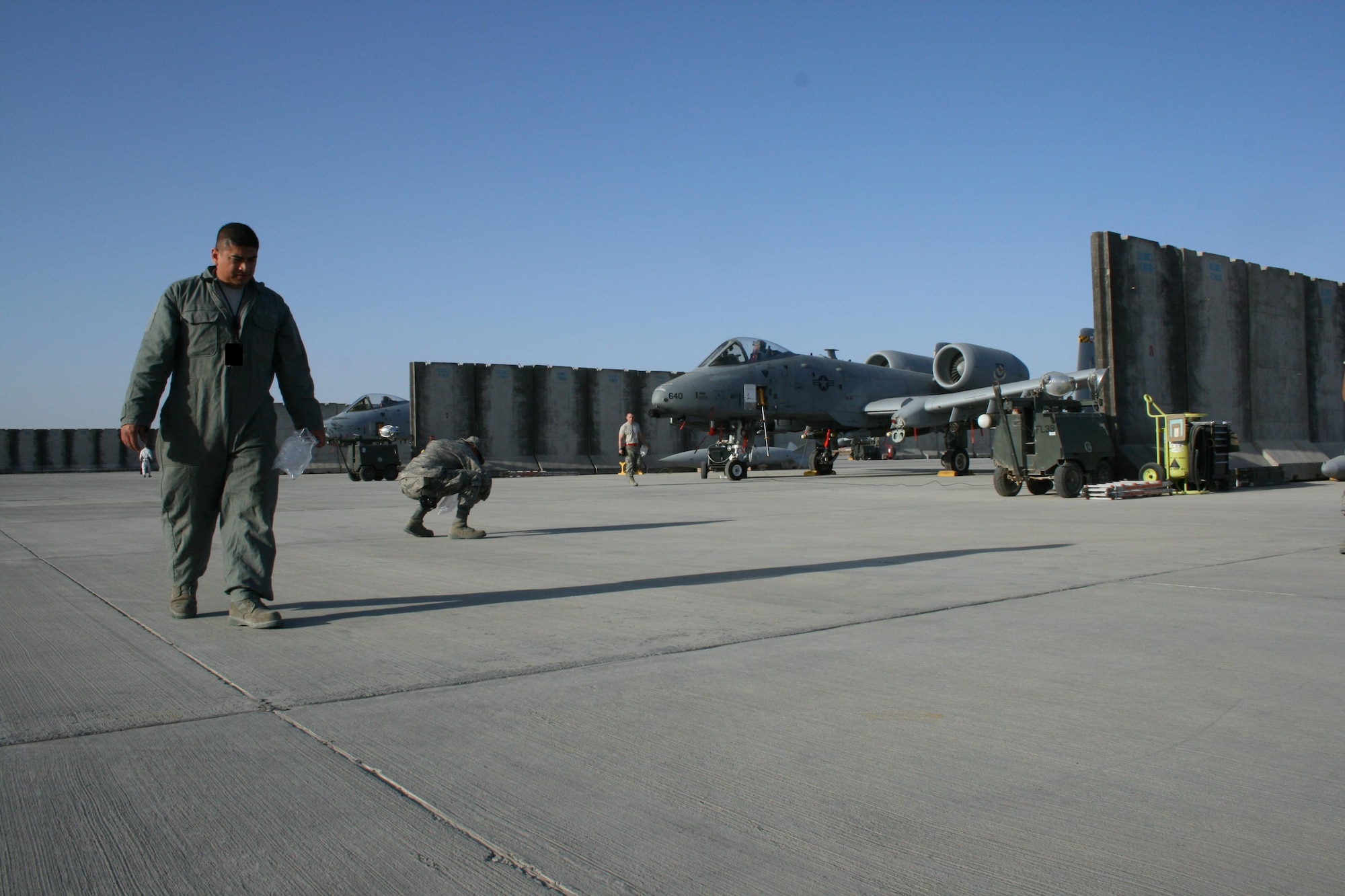 Members of the 451st Air Expeditionary Wing search the A-10C ramp for foreign objects and debris at Kandahar Airfield, Afghanistan. The FOD walk ensures that small items are removed from the ramp so they cannot be ingested into the plane's engine and cause damage. (U.S. Air Force photo by David Speicher/Released)