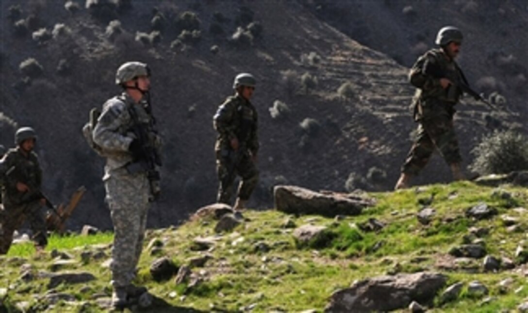 U.S. Army Staff Sgt. James R. Clark, a section sergeant with 2nd Platoon, Bear Troop, 3rd Squadron, 61st Cavalry Regiment, Task Force Destroyer, watches as Afghan National Army soldiers with 1st Kandak, 2nd Brigade walk toward Nangal village in the Naray district of eastern Afghanistan's Kunar province on March 8, 2010.  International Security Assistance Forces are providing support for the mission, which helped the Afghan National Army familiarize itself with the area.  