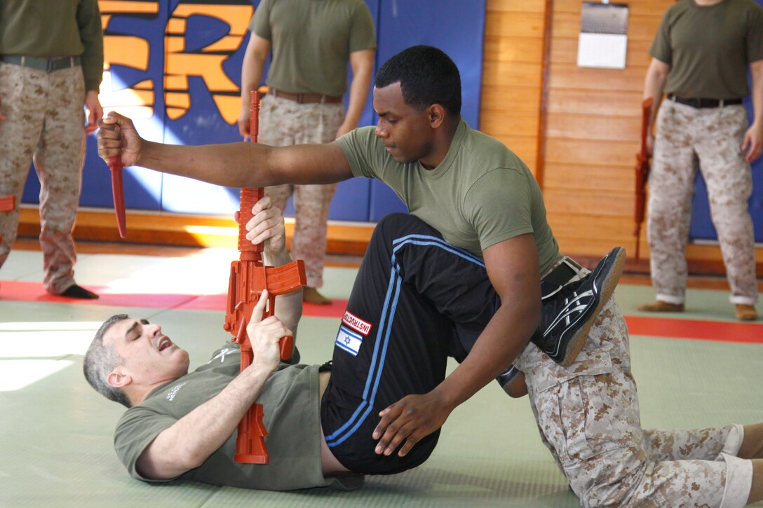 David Kahn, Israeli Krav Maga Association U.S. chief instructor and IKMA board member, demonstrates with Sgt. Rajir Douglas, a Marine with Marine Aviation Logistics Squadron 12, how to defend against a knife attack while on the ground during a two-week-long Israeli Krav Maga course held here March 22 through April 2. Krav Maga translated means “contact combat” or “close combat” and is a hand-to-hand combat system developed in Israel during the late 1940s.