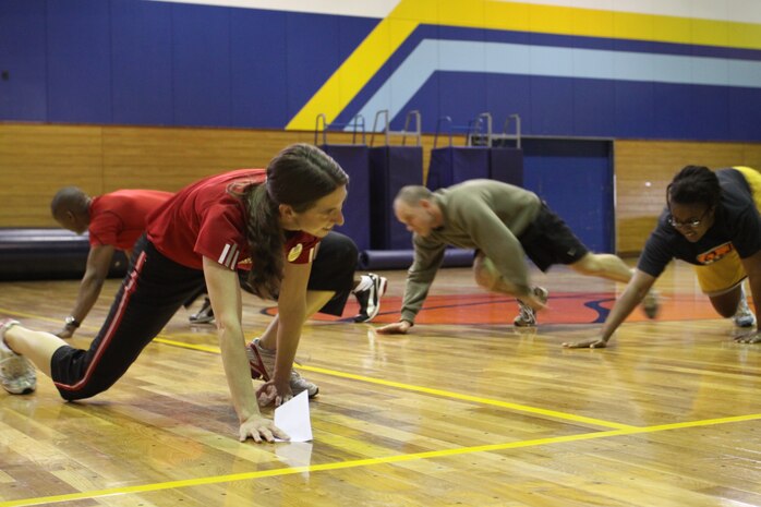 Alma Dickinson, health promotions director, demonstrates proper exercise techniques to help improve Marine Corps fitness during the Semper Fit Combat Fitness Course at IronWork’s Gym here March 24-25.