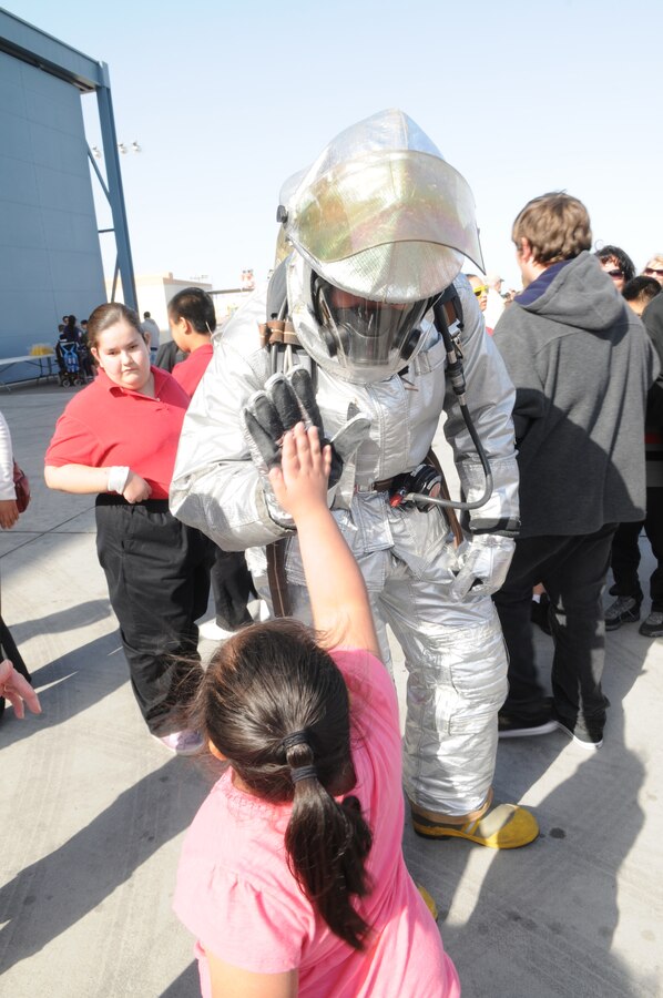 Angel Cotto, Gwyneth Ham Elementary School student, high-fives Pfc. Tyler Giersch, aircraft rescue and firefighting truck operator, on the flight line at the Marine Corps Air Station in Yuma, Ariz., during a 2010 Yuma Air Show preview for local schoolchildren March 26, 2010. The station opened its gates to approximately 200 local students and schoolteachers so they could talk to Marines and catch a sneak peek of the aircraft, such as the Pitts S-2B and F-16 Fighting Falcon. “The best part was seeing the planes take off,” said Tim Silva, Gila Vista Junior High School student. “I’ve never been so close to a jet before.”