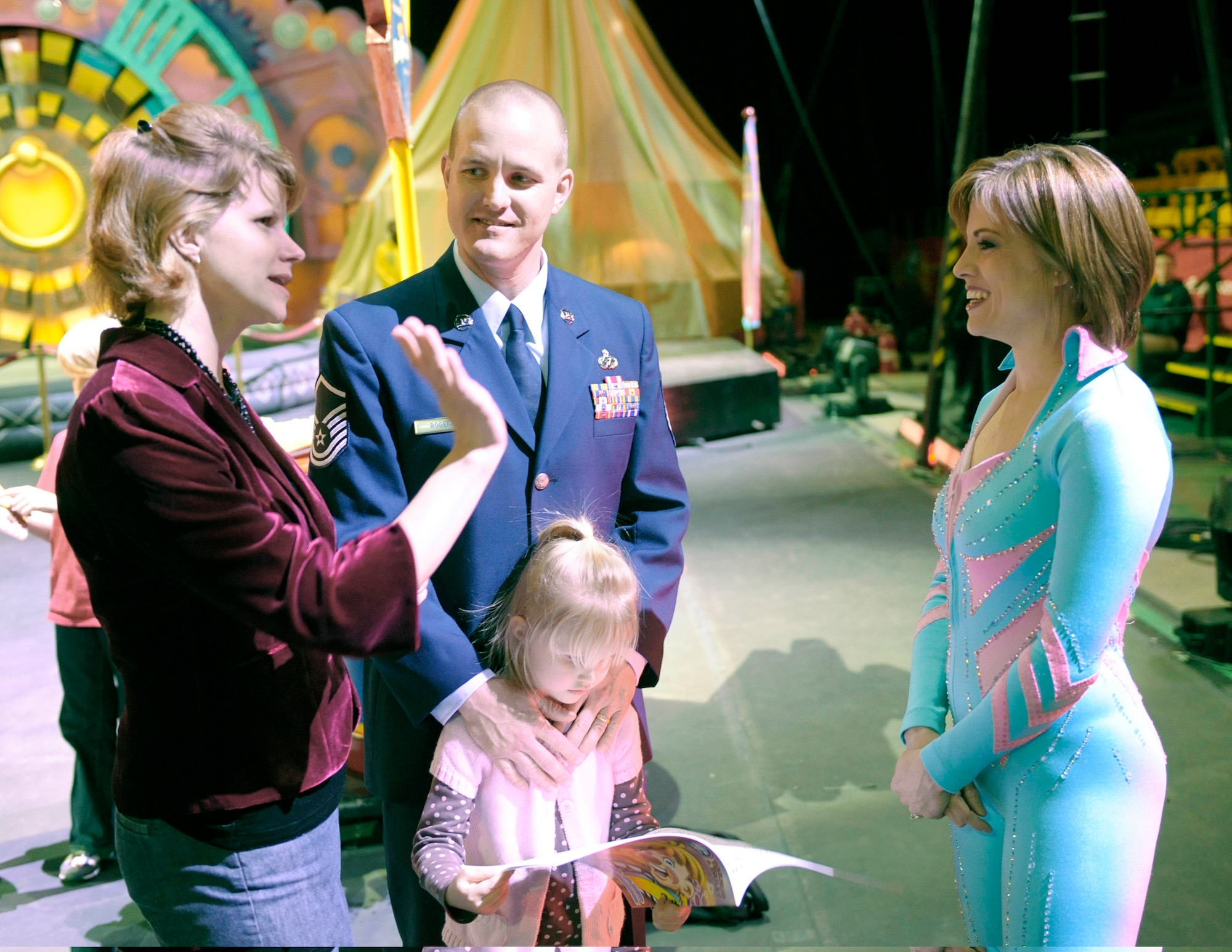 Master Sgt. Cameron Rogers looks on as his wife Maggie talks with circus human cannonball and former Air Force reservist Tina Miser March 26, 2010, prior to the start of the Ringling Bros. and Barnum & Bailey "Zing Zang Zoom" circus performance at George Mason University's Patriot Center in Fairfax, Va. Their 5-year-old daughter Laine is checking out the program. Sergeant Rogers is the Air Force District of Washington's UH-1N helicopter program manager at Bolling Air Force Base, D.C. The Rogers family was invited to serve as guest circus ringmasters representing military families worldwide in observance of Year of the Air Force Family. (U.S. Air Force photo/Jim Varhegyi)