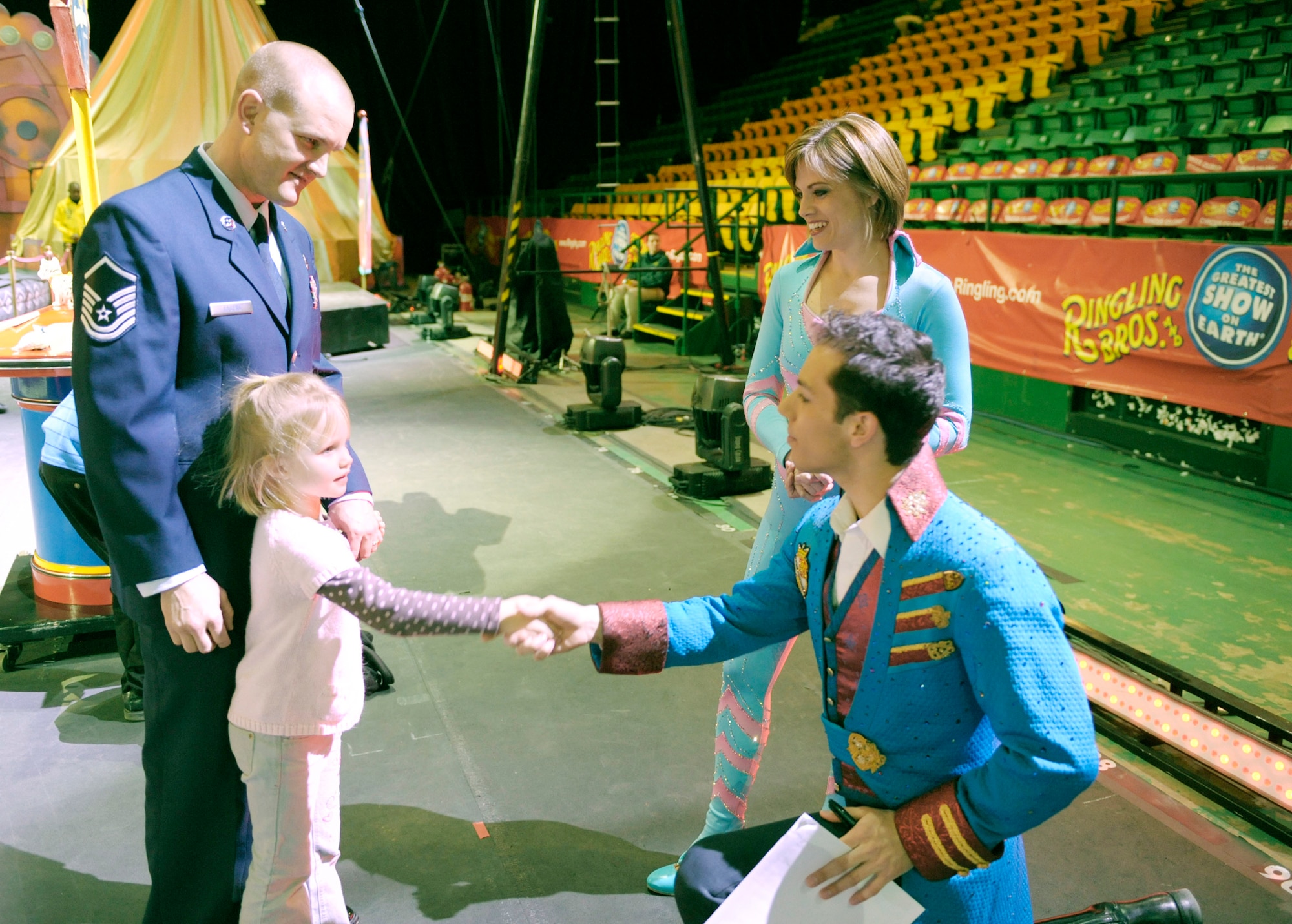 Master Sgt. Cameron Rogers looks on as his 5-year-old daughter Laine shakes hands with Magical Zingmaster Alex Ramon prior to the start of the Ringling Bros. and Barnum & Bailey "Zing Zang Zoom" circus performance March 26, 2010, at George Mason University's Patriot Center in Fairfax, Va.  Looking on is the circus' human cannonball and former Air Force reservist Tina Miser. Sergeant Rogers is the Air Force District of Washington's UH-1N helicopter program manager at Bolling Air Force Base, D.C. The Rogers family was asked to serve as guest circus ringmasters representing military families worldwide in observance of Year of the Air Force Family. (U.S. Air Force photo/Jim Varhegyi)