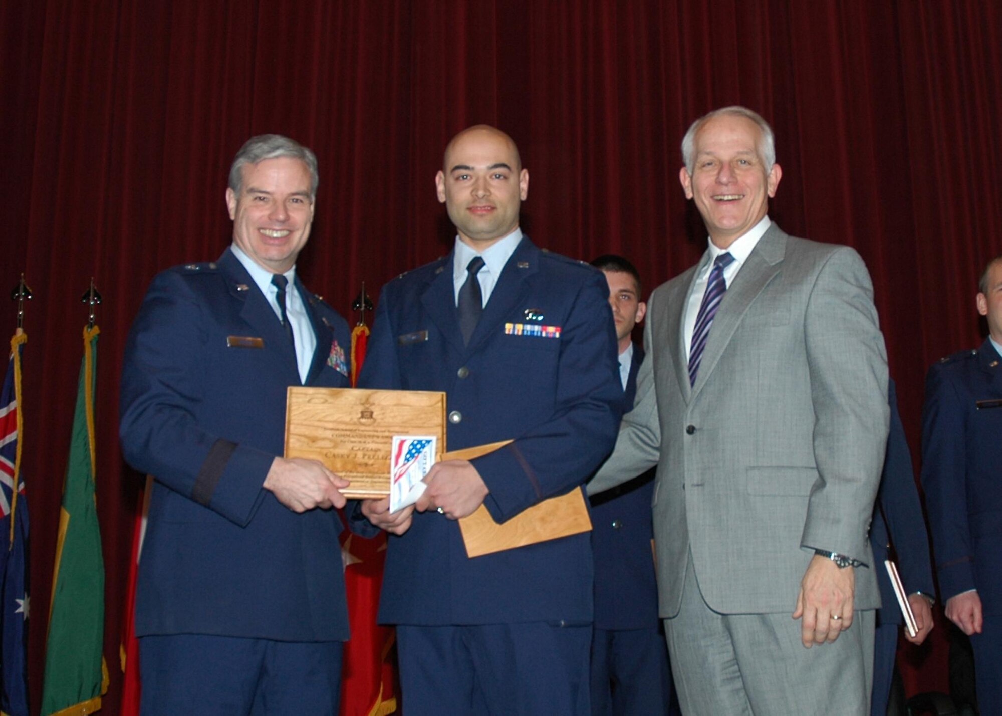 The Air Force Institute of Technology Commandant Brig. Gen. Walter D. Givhan (left) along with Maj. General (Ret.) Michael C. Mushala presented the Commandant’s award to Capt. Casey Pellizzari at the AFIT awards ceremony, March 25 at Wright-Patterson Air Force Base, Ohio. (U.S. Air Force photo/Bob Memering)