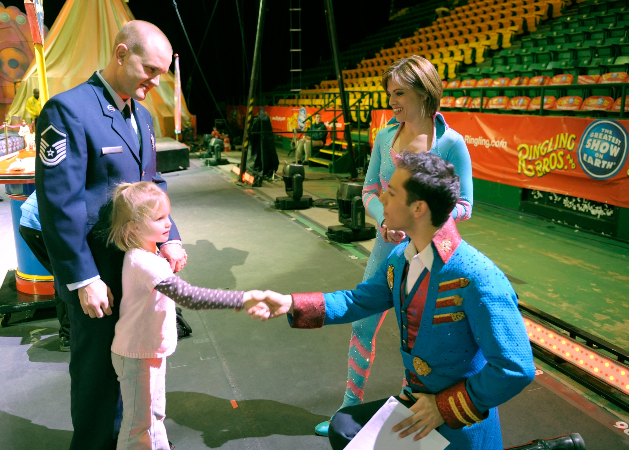 Air Force Master Sgt. Cameron Rogers (left) looks on as his 5-year-old daughter Laine shakes hands with Magical Zingmaster Alex Ramon prior to the start of the  Ringling Bros.   and Barnum & Bailey "Zing Zang Zoom" circus performance at George Mason University's Patriot Center March 26, 2010, Fairfax, Va. Looking on from the right is the circus' human cannon ball and former Air Force Reservist Tina Miser. Sergeant Rogers and his family served as guest ringmasters for the circus performance.  Sergeant Rogers recently returned from a year-long deployment to Afghanistan and currently is the Air Force District of Washington's UH-1N helicopter program manager at Bolling Air Force Base, Washington. The Rogers family was asked to serve as guest circus ringmasters representing military families worldwide in observance of Year of the Air Force Family. (U.S. Air Force photo/Jim Varhegyi)