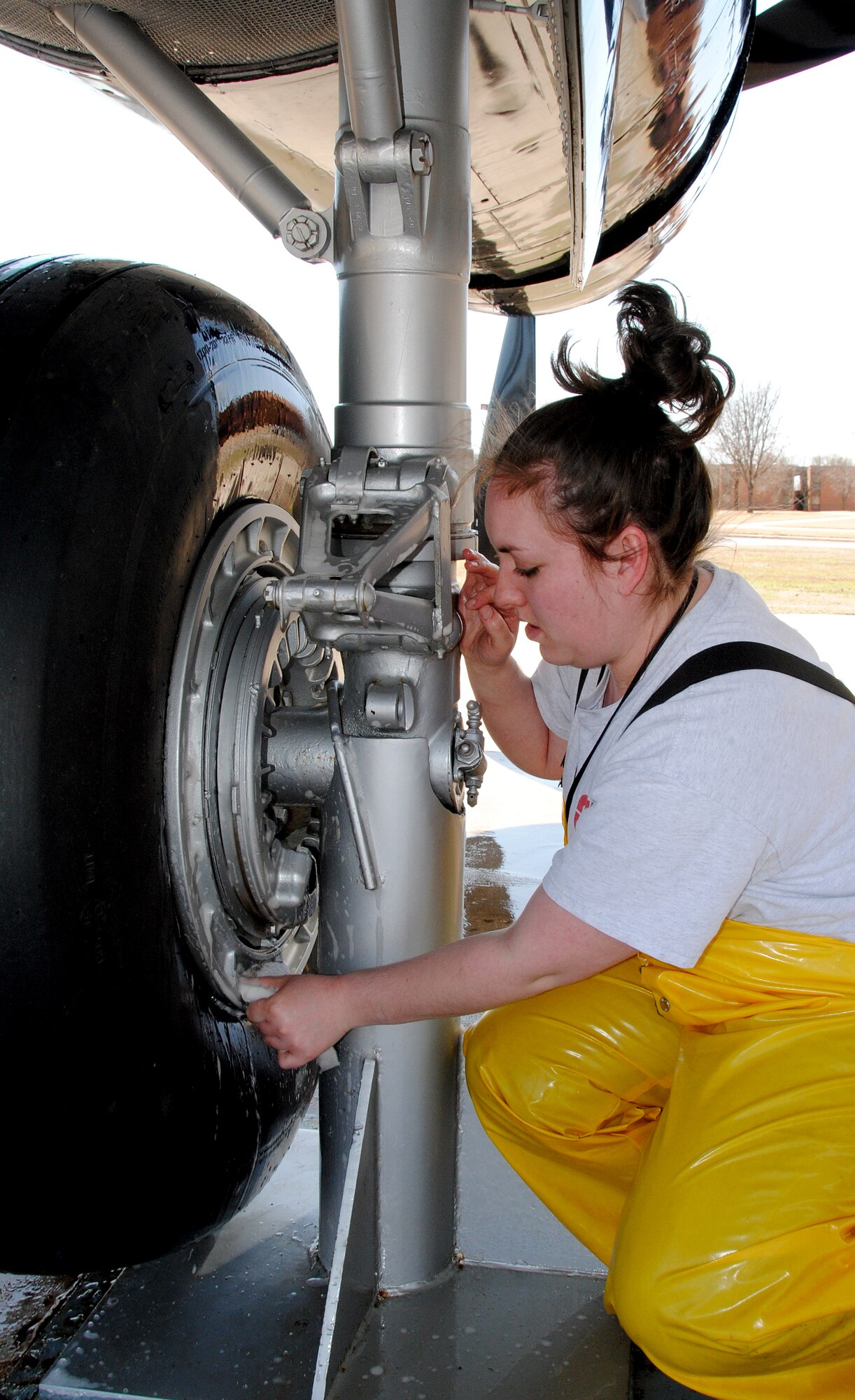 Randi Malaska, with the CSC Applied Technologies aircraft maintenance wash rack team, cleans the wheel of the A-26 Invader static-display aircraft at Vance AFB during its six-month wash down, March 29. (U.S. Air Force photo/ Joe B. Wiles)