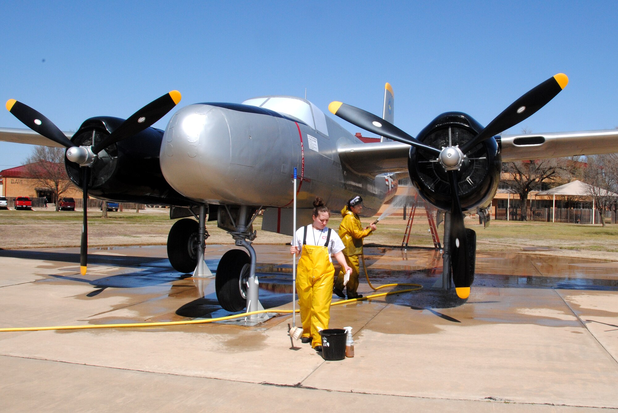 Randi Malaska, left, and Spencer Cahoon, with the CSC Applied Technologies aircraft maintenance wash rack team, wash down the A-26 Invader static-display aircraft during its six-month cleaning, March 29. (U.S. Air Force photo/ Joe B. Wiles)