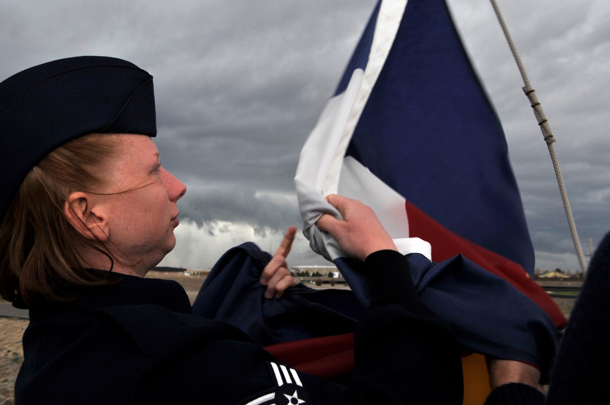 BUCKLEY AIR FORCE BASE, Colo. -- Senior Airman Kristin Porter, Air Force Technical Applications Center Detachment 45, takes down the Colorado state flag at Buckley Airman Leadership School March 22. ALS trains today's Airmen to become tomorrow's leaders. (U.S. Air Force photo by Senior Airman Kathrine McDowell)