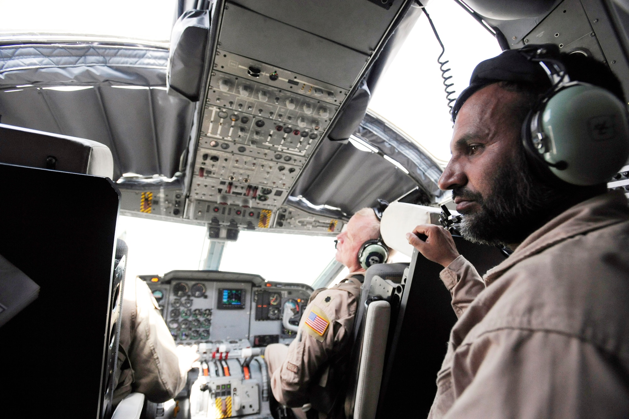 Afghanistan National Army Air Corps Master Sgt. Sheer Aqa Karimi listens to the pilots while performing loadmaster duties for Brig. Gen. Michael Boera (left) and Lt. Col. Chris Kampsen prior to taking off for an operational mission and C-27 Spartan loadmaster check ride March 28, 2010, at Camp Bastion, Afghanistan. During the flight, a loadmaster assists the pilot by running checklists and checking engine and hydraulic systems to ensure passengers and cargo arrive at their destination safely. Sergeant Karimi is a a C-27 loadmaster. General Boera is the 438th Air Expeditionary Wing and Combined Air Power Transition Force commander, and Colonel Kampsen is the director of operations for the 538th Air Expeditionary Advisory Squadron and a C-27 instructor. (U.S. Air Force photo/Staff Sgt. Manuel J. Martinez)