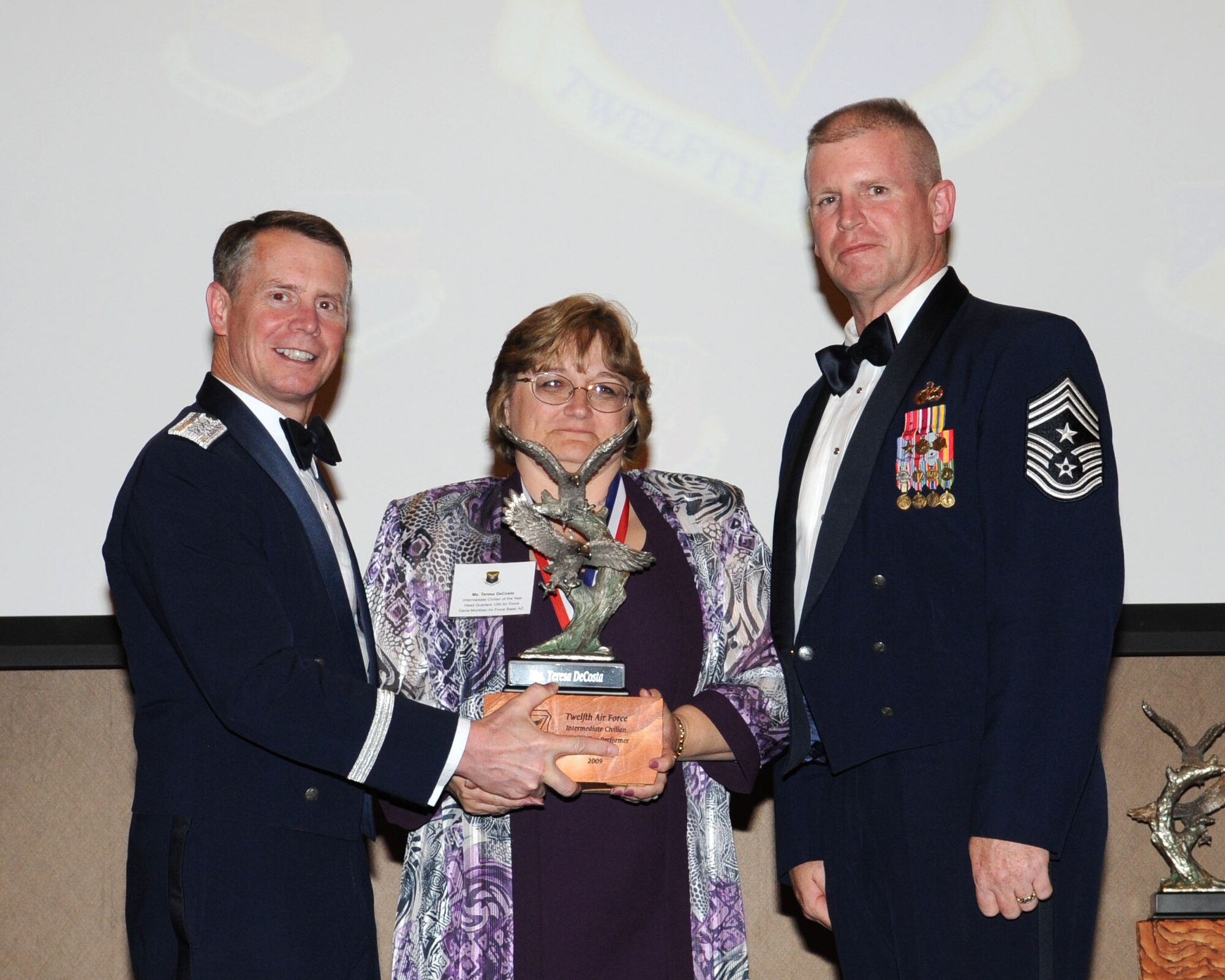 DAVIS-MONTHAN AIR FORCE BASE, Ariz. -- Lt. Gen. Glenn Spears (left), 12th Air Force (Air Forces Southern) commander, and Chief Master Sgt. Harold Clark (right), 12th AF (AFSOUTH) command chief, present the Outstanding Performer of the Year award to Ms. Teresa DeCoste Mar. 9. Ms. DeCoste is from Headquarters 12th AF, Davis-Monthan Air Force Base, Ariz.  (U.S. Air Force Photo by Airman Jerilyn Quintanilla)